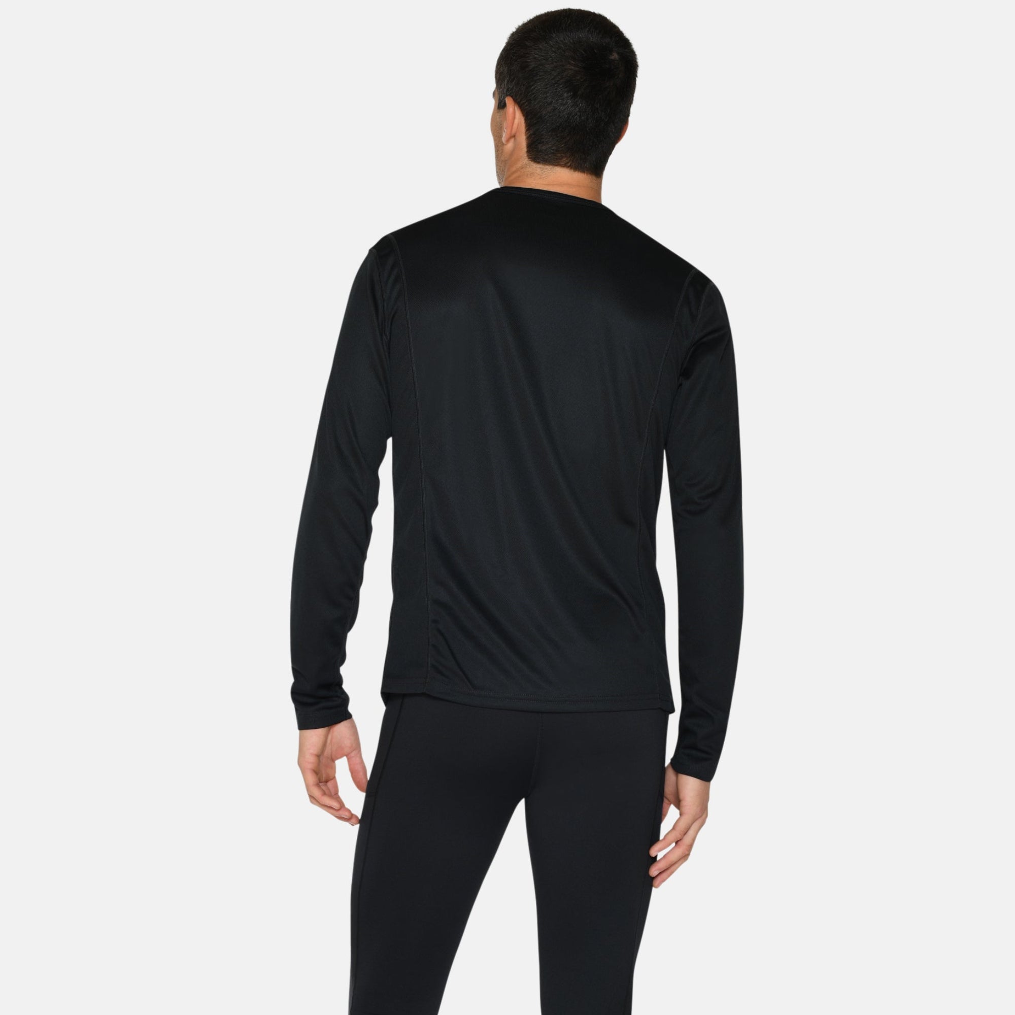 Eine Person steht mit dem Gesicht nach hinten, trägt ein schwarzes langärmeliges Hemd, schwarze Leggings und blaue Laufschuhe mit weißen Sohlen auf einem einfarbig weißen Hintergrund.