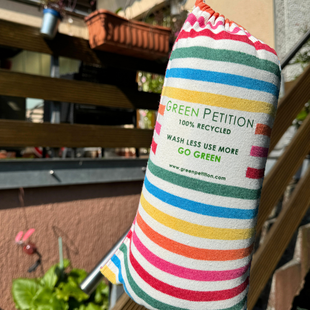 Gestreifter Stoffbeutel mit dem Text "Green Petition, 100% Recycled, Wash Less Use More, Go Green", draußen aufgenommen.