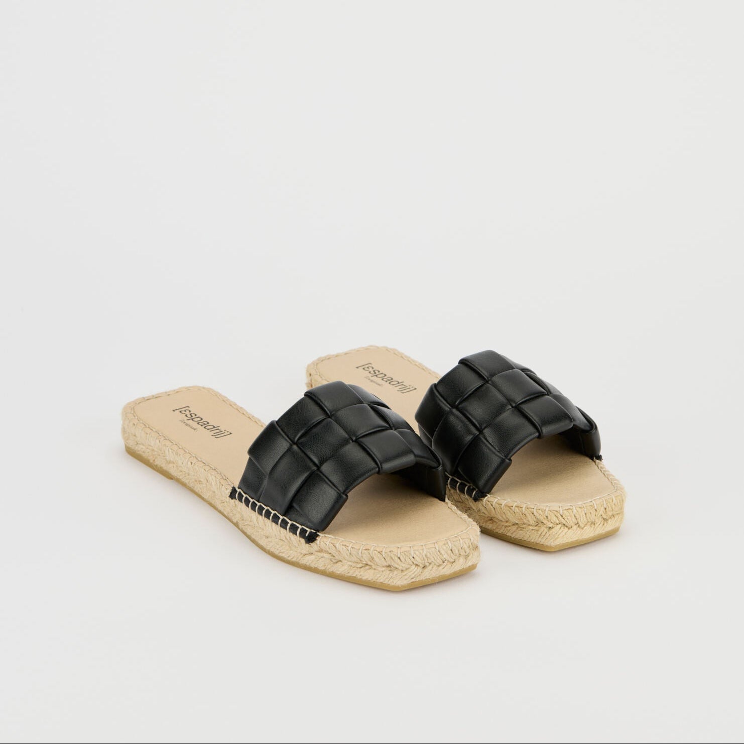 Schwarze, geflochtene Sandalen mit beigem, geflochtenem Fußbett auf weißem Hintergrund.