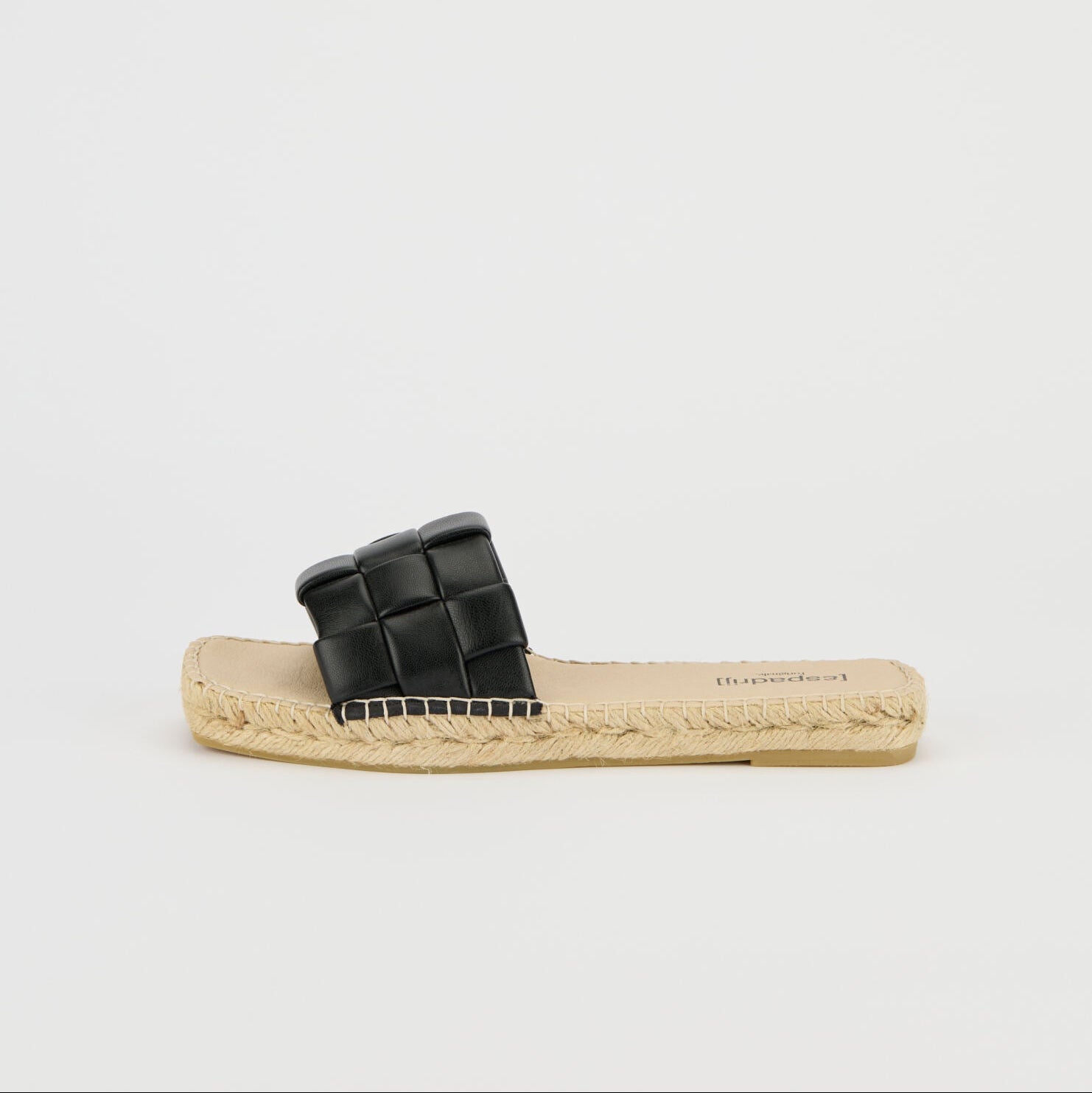 Schwarze Sandale mit geflochtenem Riemen und beiger Bastsohle auf weißem Hintergrund.