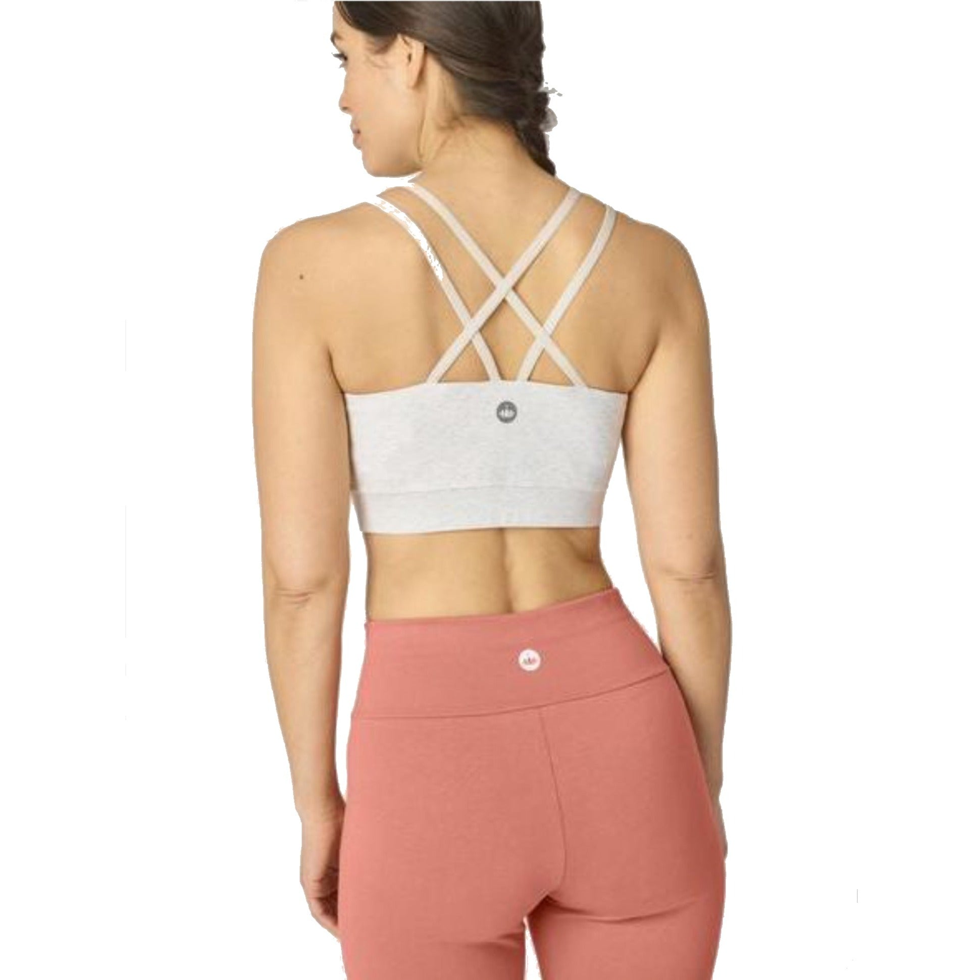 Frau in Fitnesskleidung zeigt Rückenansicht mit überkreuzten Trägern eines Sport-BHs und rosa Leggings.