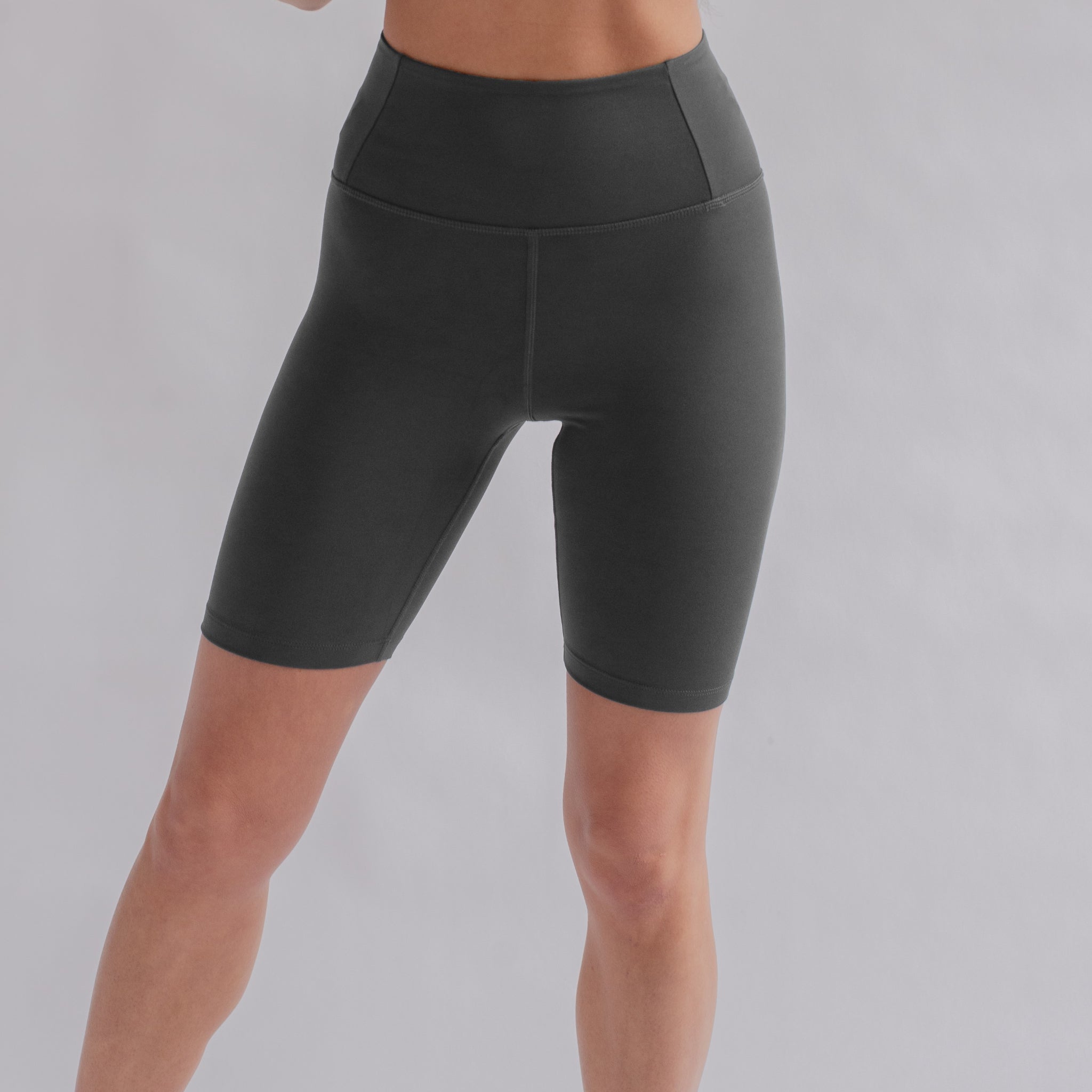 Person trägt schwarze Sportshorts vor grauem Hintergrund.