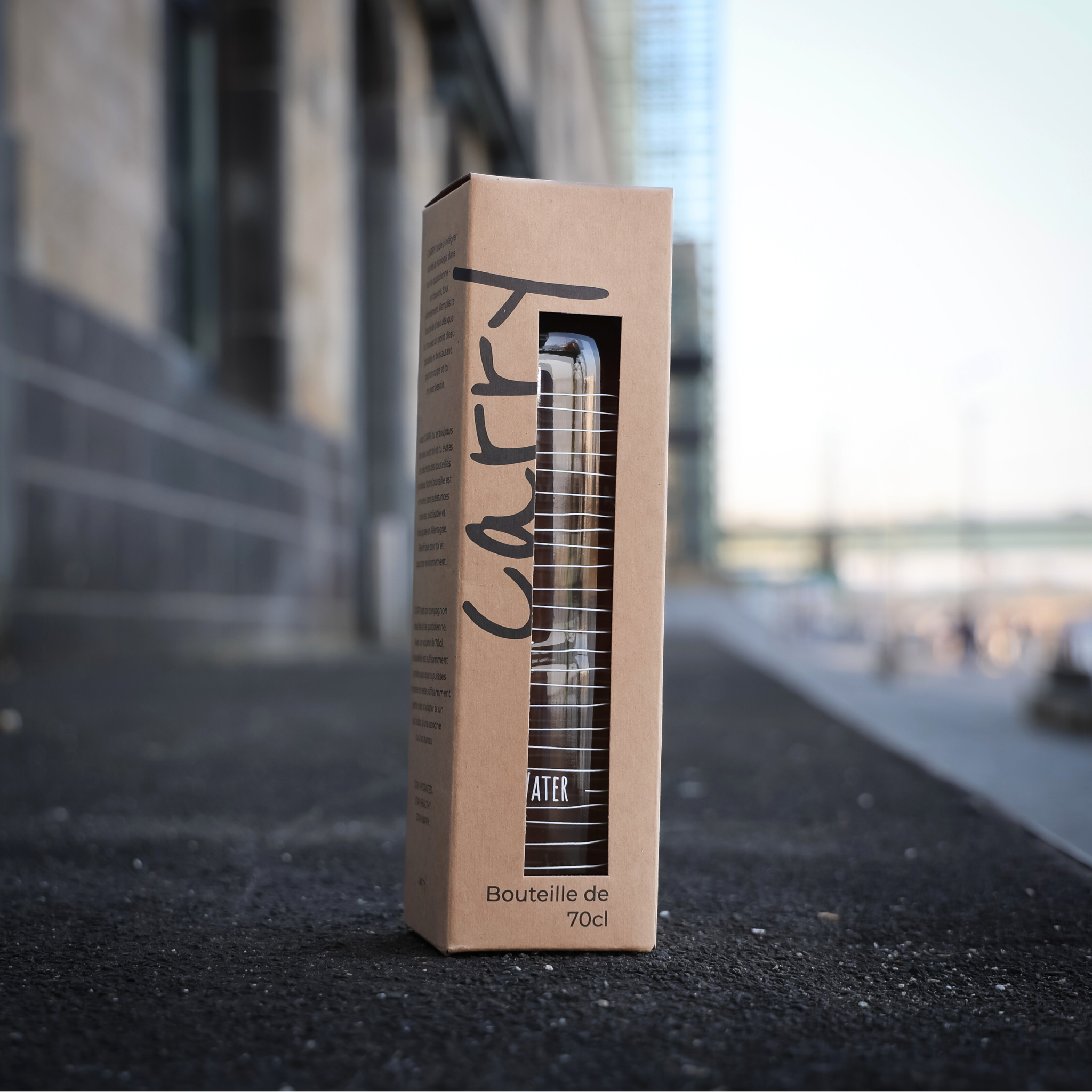 Pappschachtel mit der Aufschrift "Carry", die eine Flasche mit 70 cl Inhalt zeigt, auf einem Bürgersteig stehend.