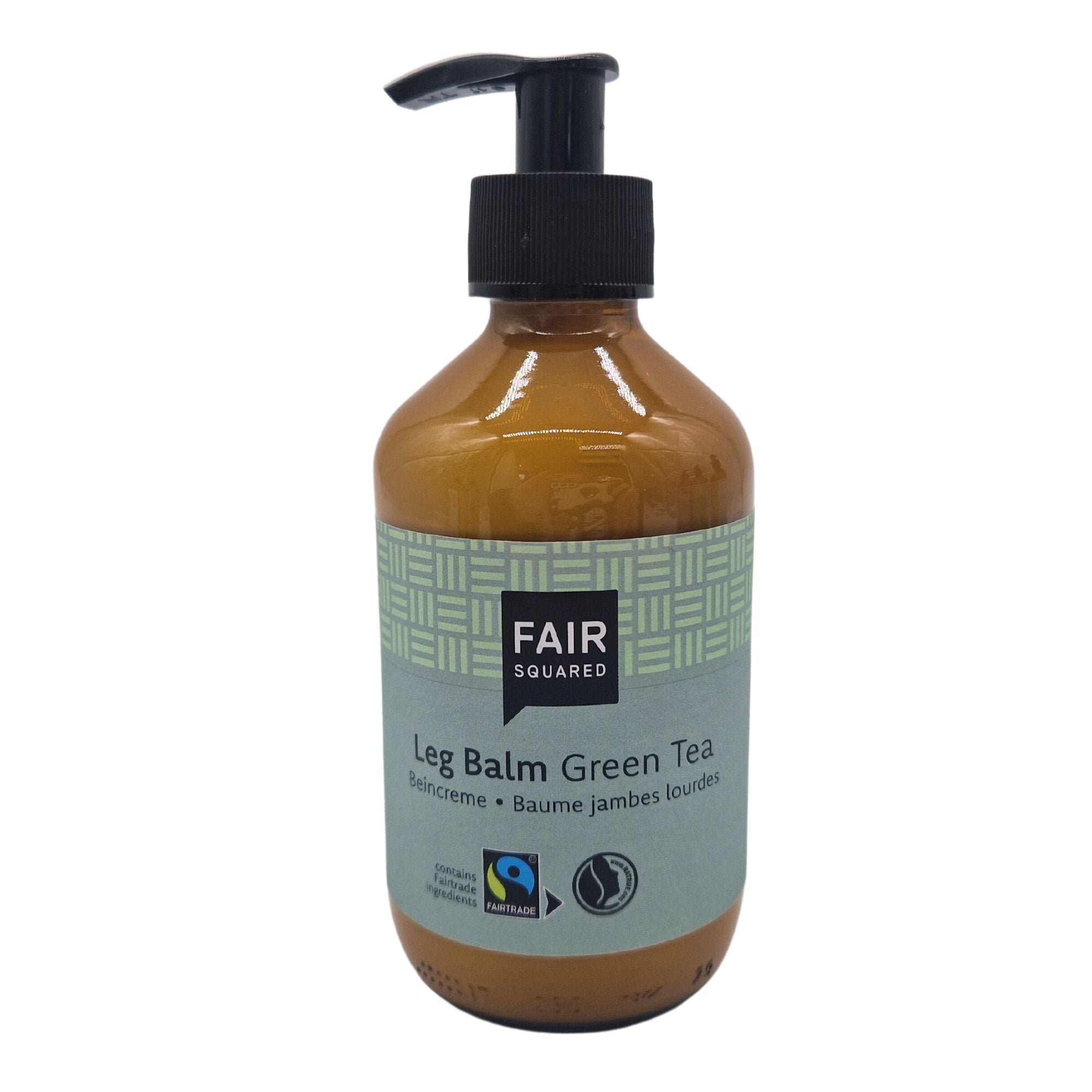 Eine braune Pumpflasche mit der Aufschrift FAIR SQUARED Leg Balm Green Tea mit Fairtrade- und Vegan-Logos und einem hellgrünen, gemusterten Design auf dem Etikett.
