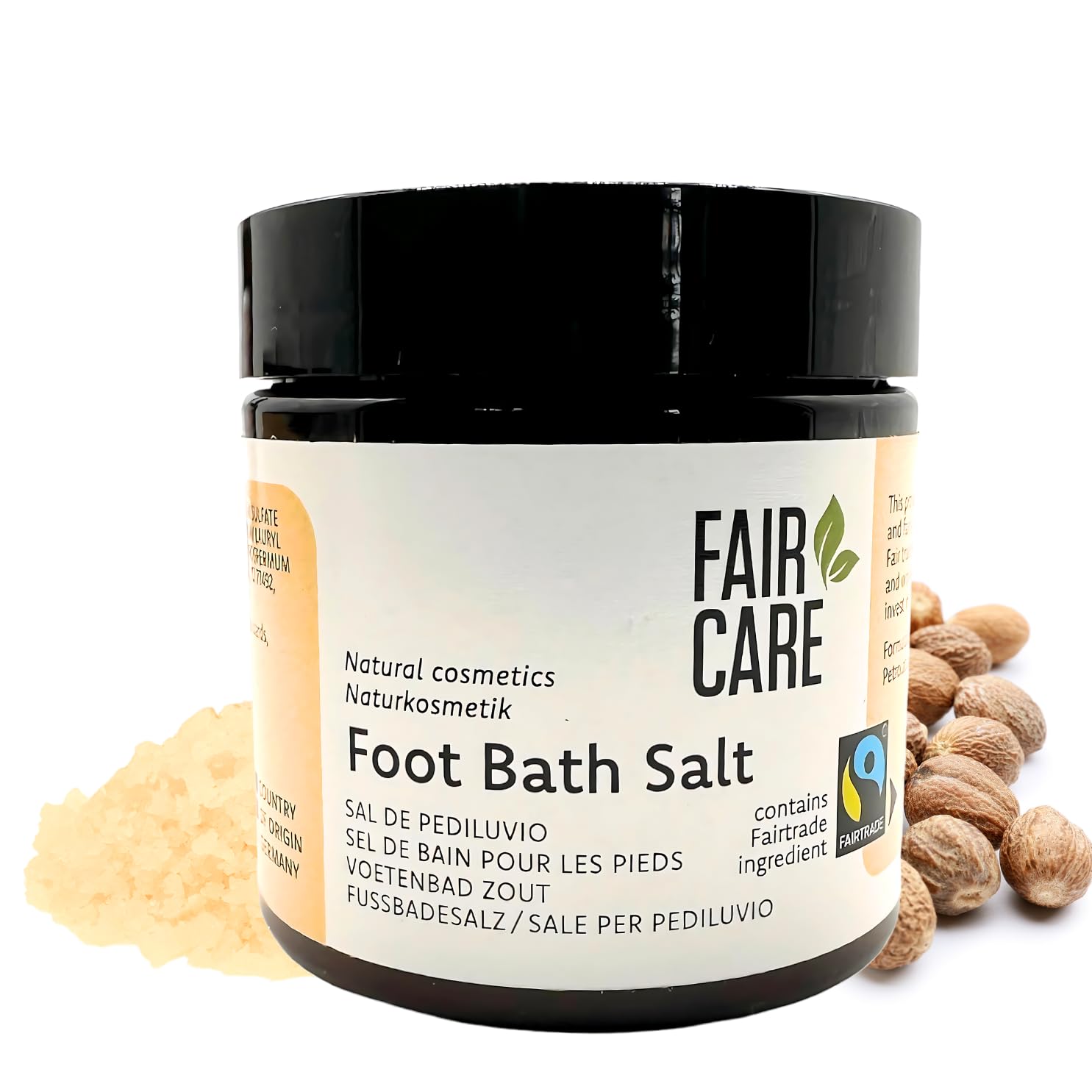 Ein Glas Fair Care Fußbadesalz mit der Aufschrift Naturkosmetik. Das Glas ist von Badesalzkristallen und ganzer Muskatnuss umgeben. Die Verpackung hebt die Fairtrade-Zutaten hervor.