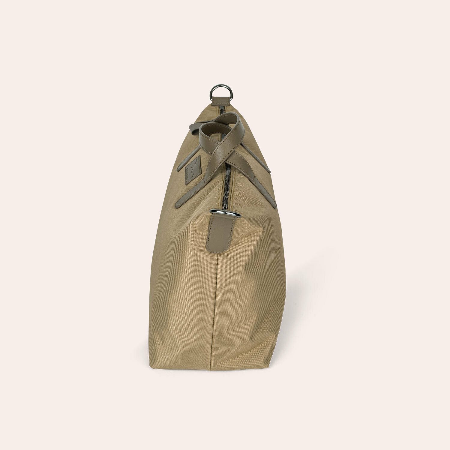 Seitenansicht einer hellbraunen, rechteckigen Tasche mit Reißverschluss, Lederriemen und silbernen Beschlägen, fotografiert vor einem schlichten hellen Hintergrund.