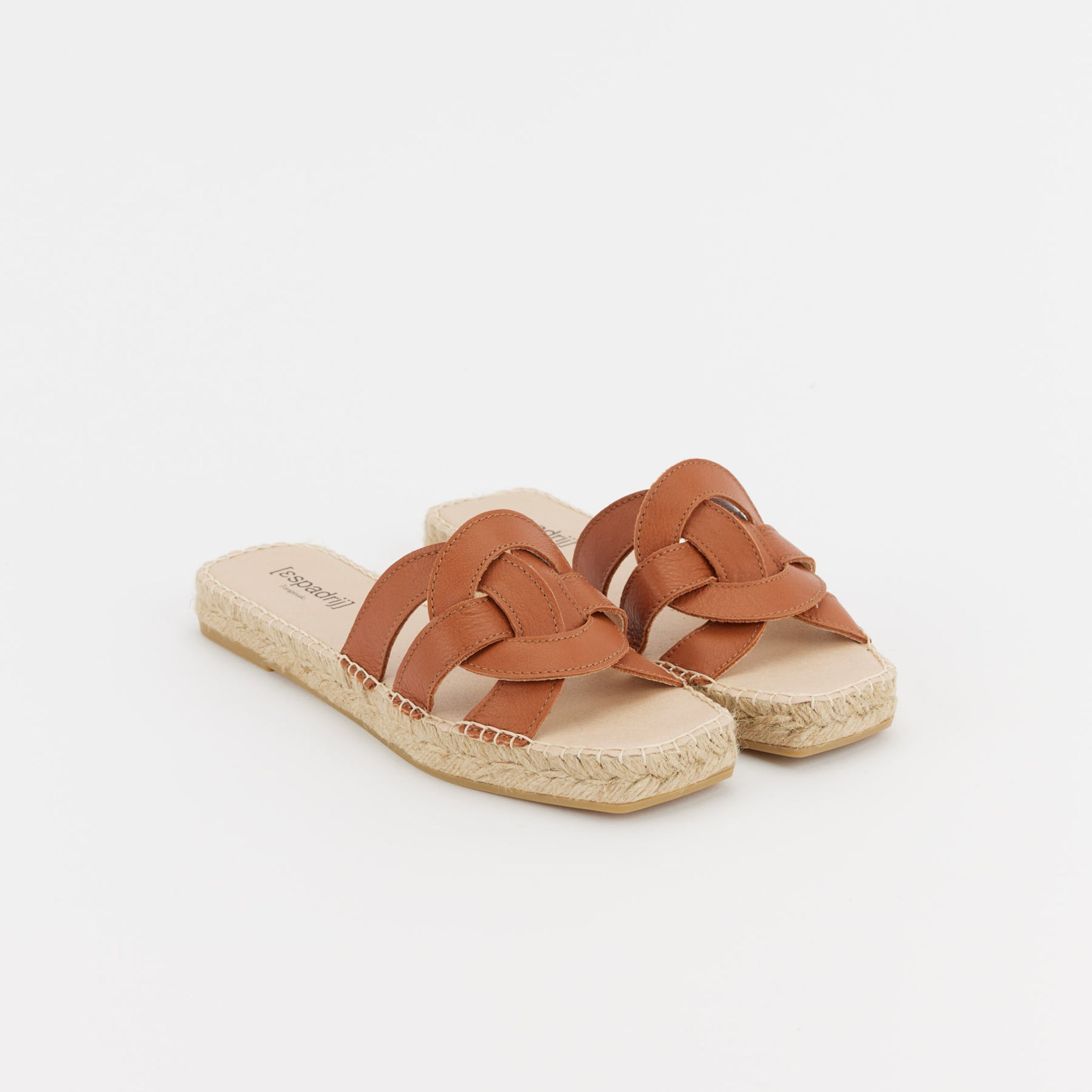 Braune Leder-Sandalen mit geflochtenem Design und geflochtener Bastsohle auf weißem Hintergrund.
