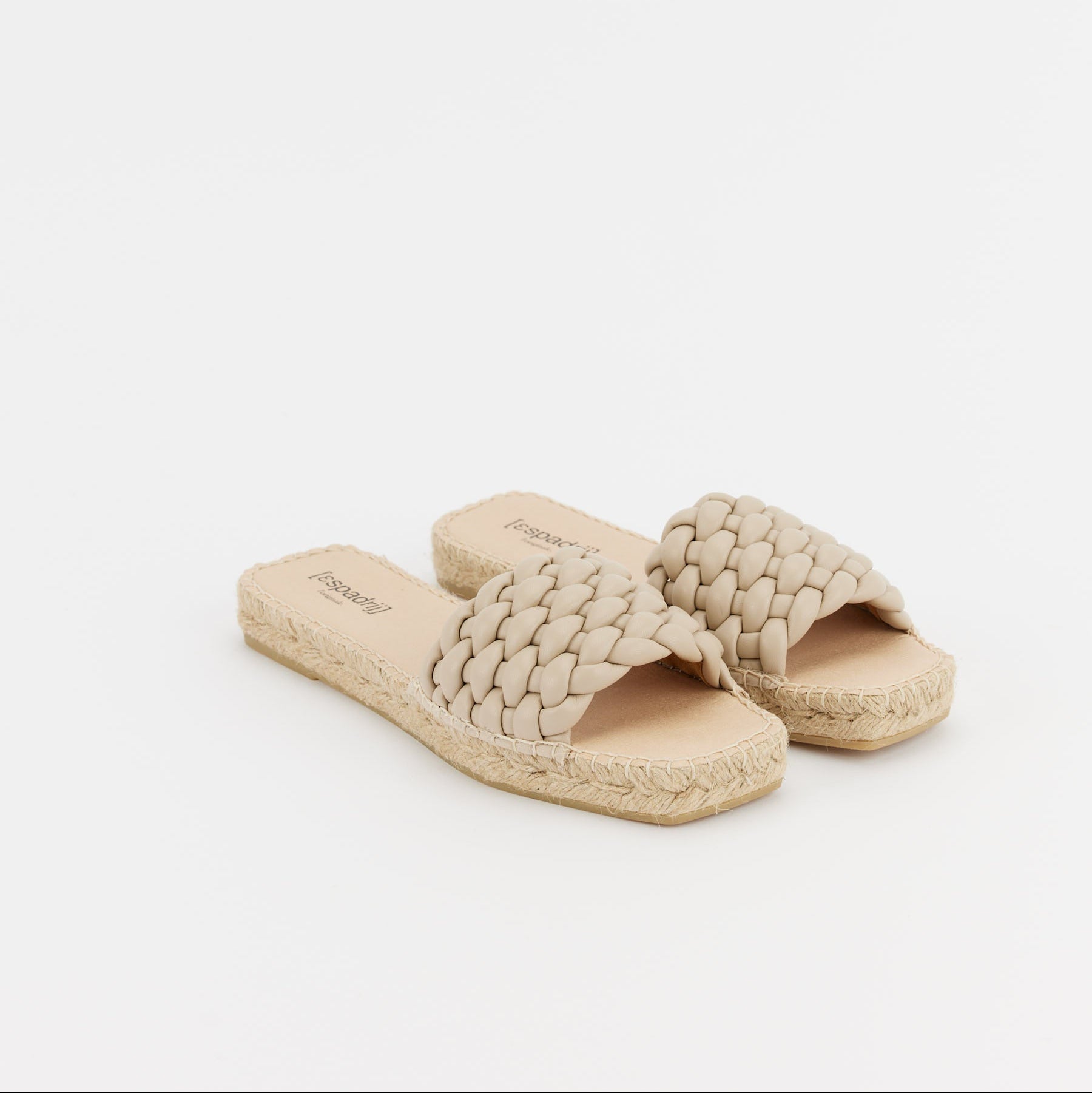 Beige geflochtene Sandalen mit Espadrille-Sohlen auf weißem Hintergrund.