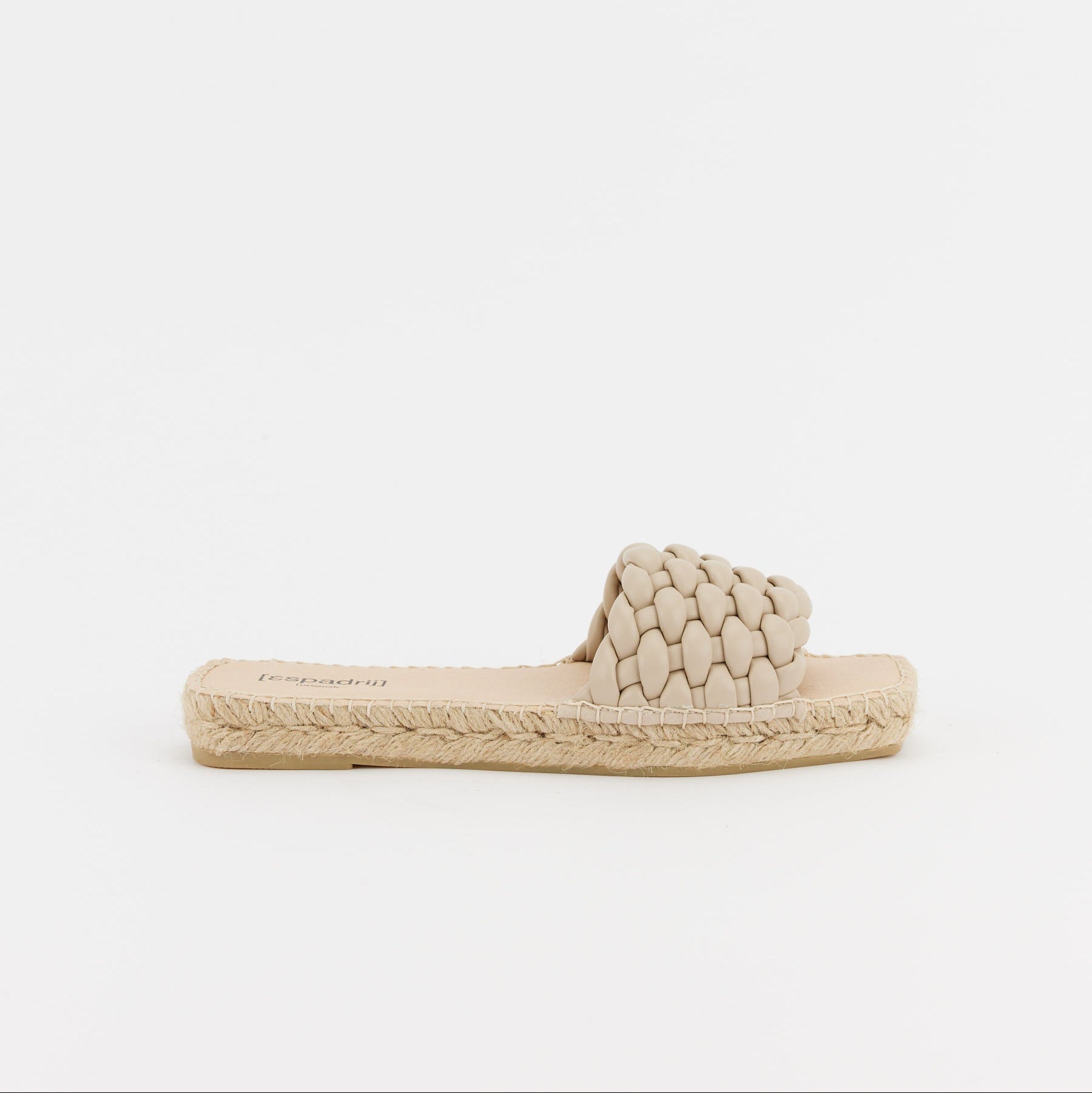 Beiger geflochtener Espadrille-Slipper mit flacher Sohle und Bastverzierung auf weißem Hintergrund.