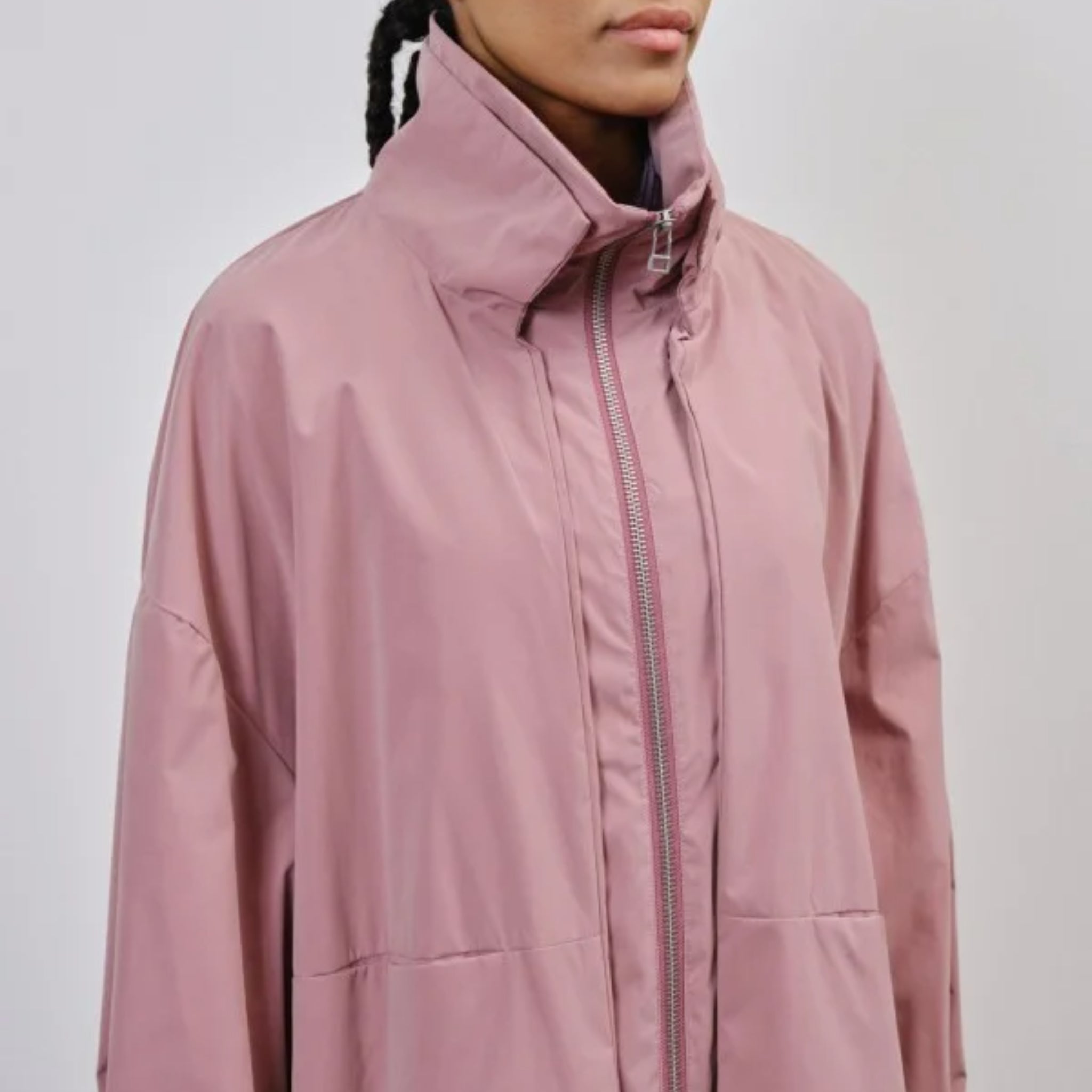 Person in a pink jacket with a high collar and zipper, facing left.