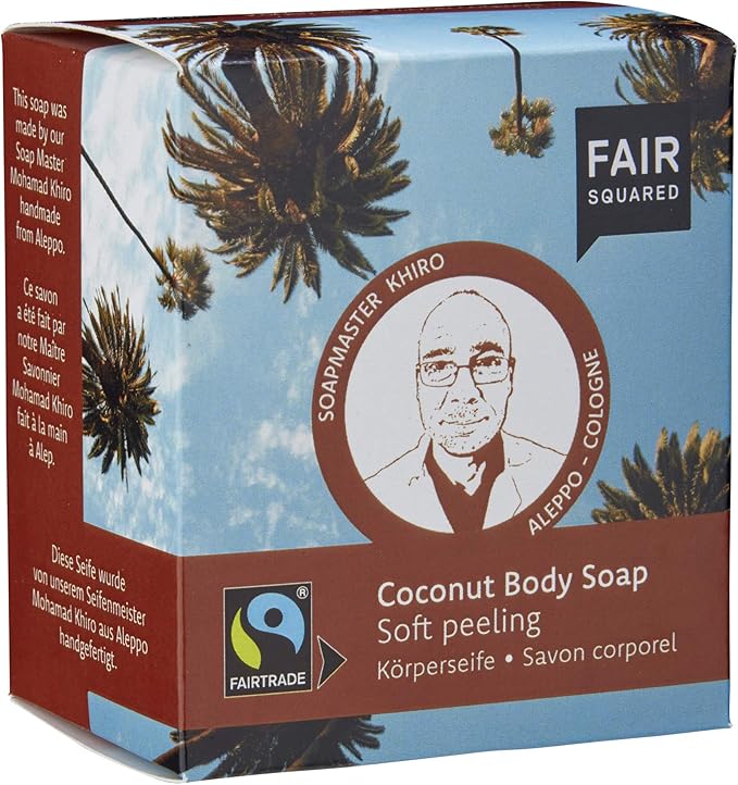 Eine Schachtel Fair Squared Coconut Body Soap, die als Soft Peeling bezeichnet wird. Die Verpackung enthält ein illustriertes Porträt von Soapmaster Khiro, Fairtrade- und Vegan-Logos sowie Text in mehreren Sprachen.