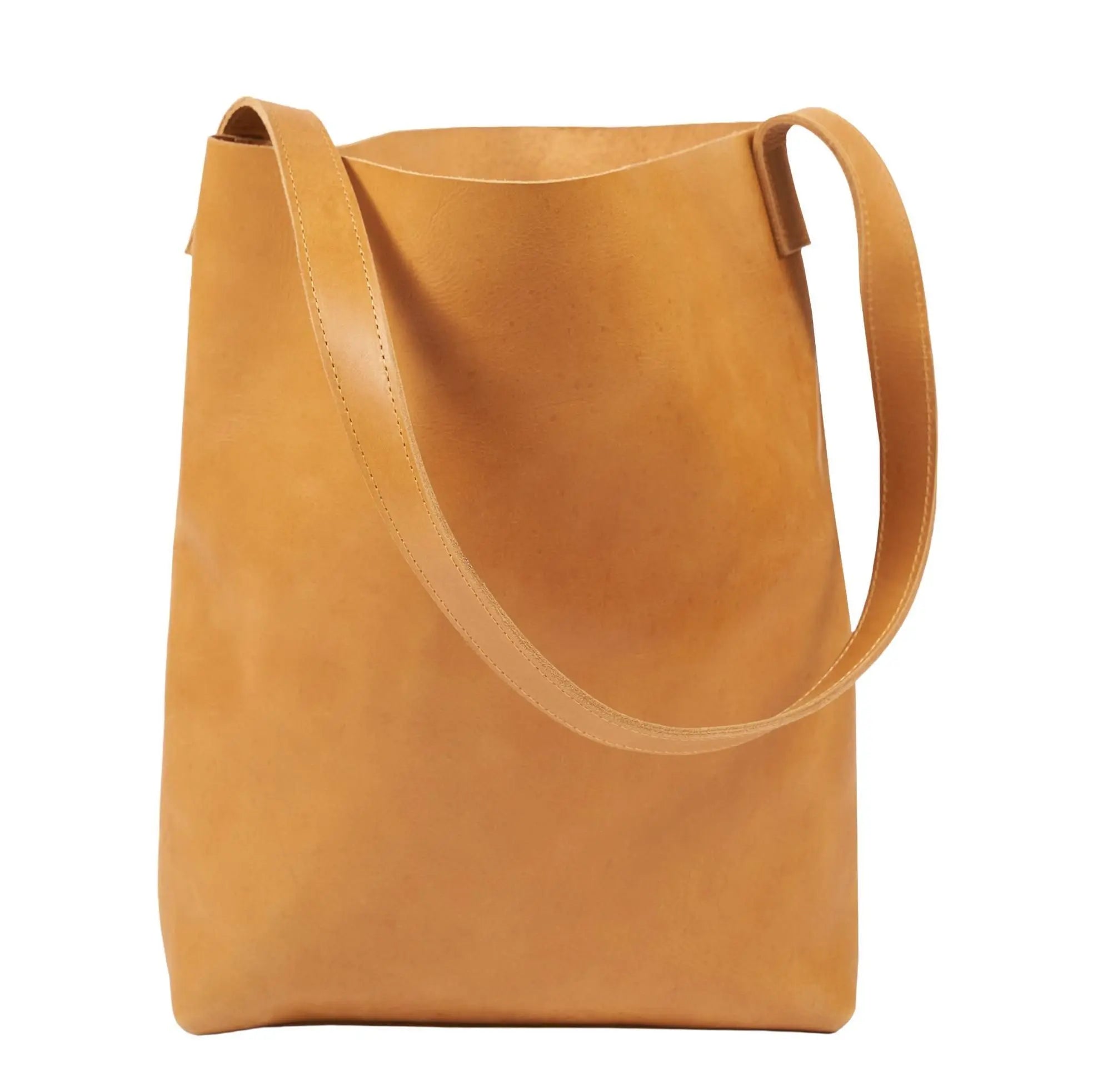 Eine minimalistische Umhängetasche aus hellbraunem Leder mit einem einzigen breiten Riemen, aufrecht stehend auf weißem Hintergrund. Die Tasche hat eine glatte, unverzierte Oberfläche und ein einfaches, modernes Design.