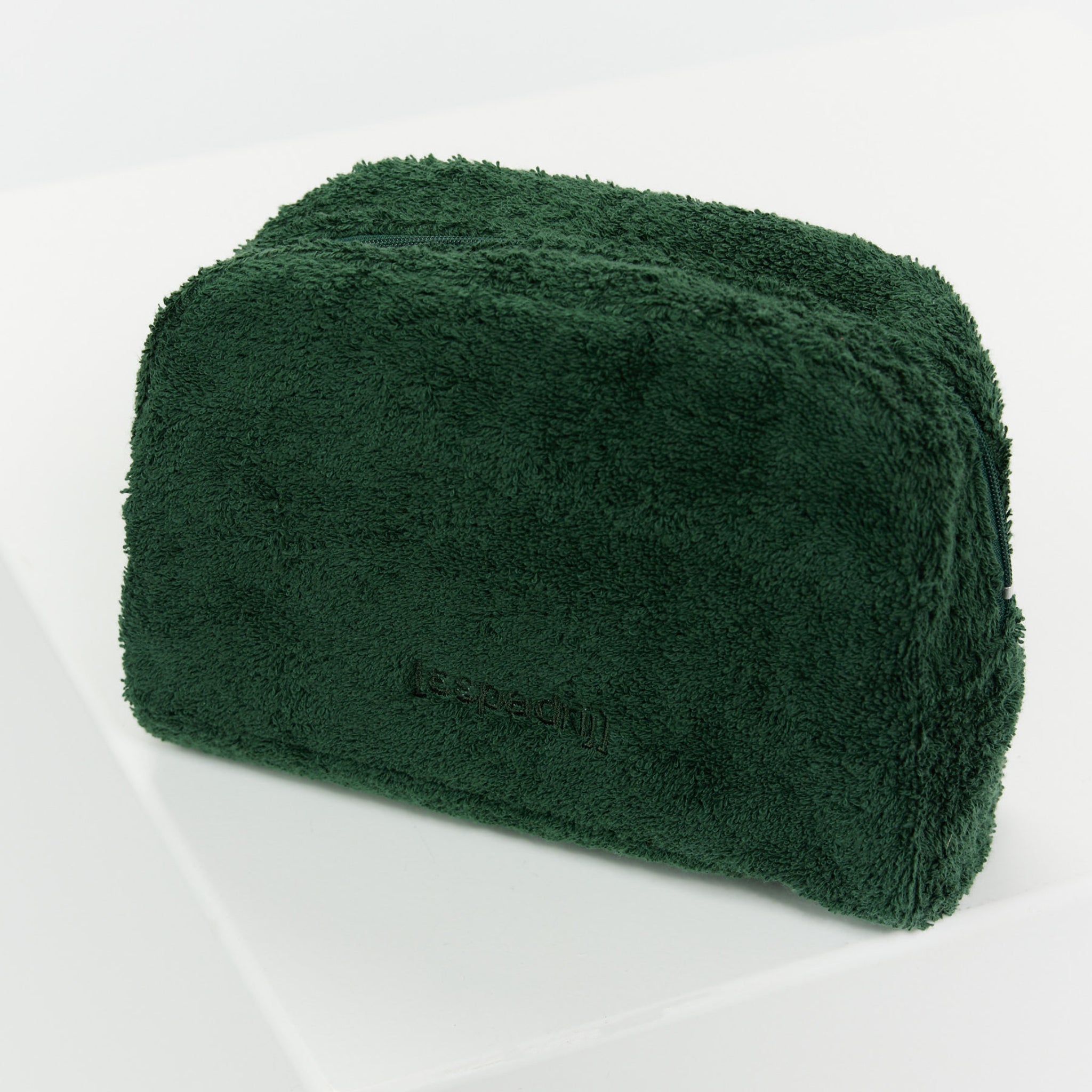 Dunkelgrüne stoffartige Kosmetiktasche mit Reißverschluss, auf einem weißen Hintergrund platziert.