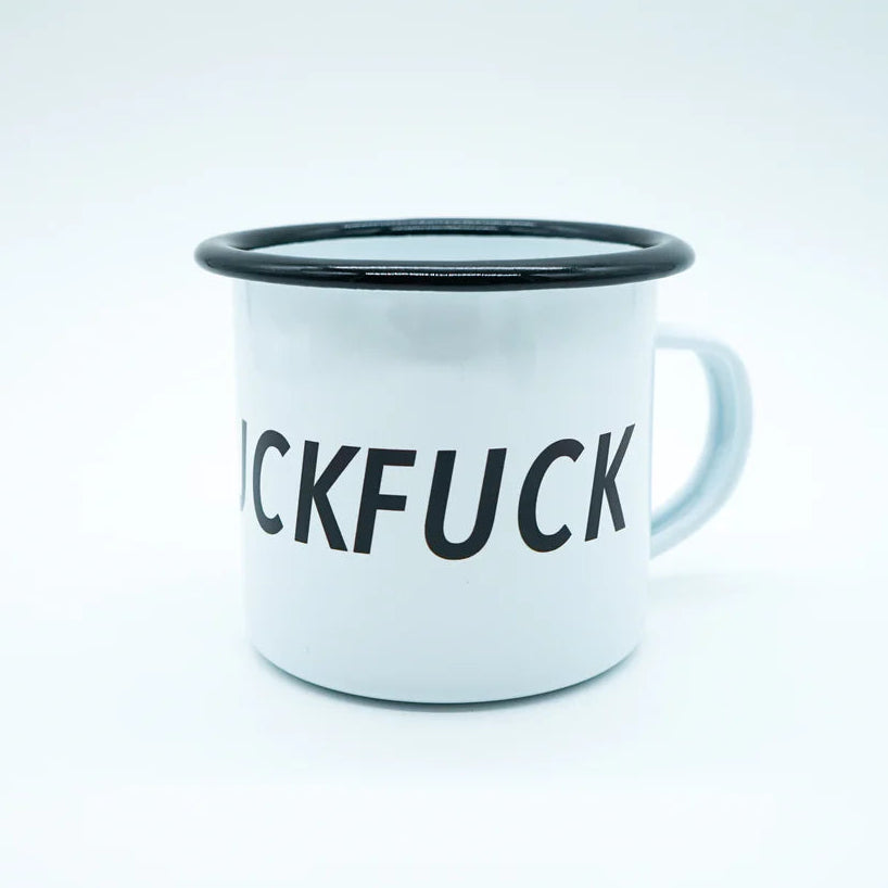 Ein weißer Emaillebecher mit schwarzem Rand, auf dessen Seite das Wort FUCK in fetten schwarzen Buchstaben teilweise sichtbar ist. Der Hintergrund ist schlicht und weiß.