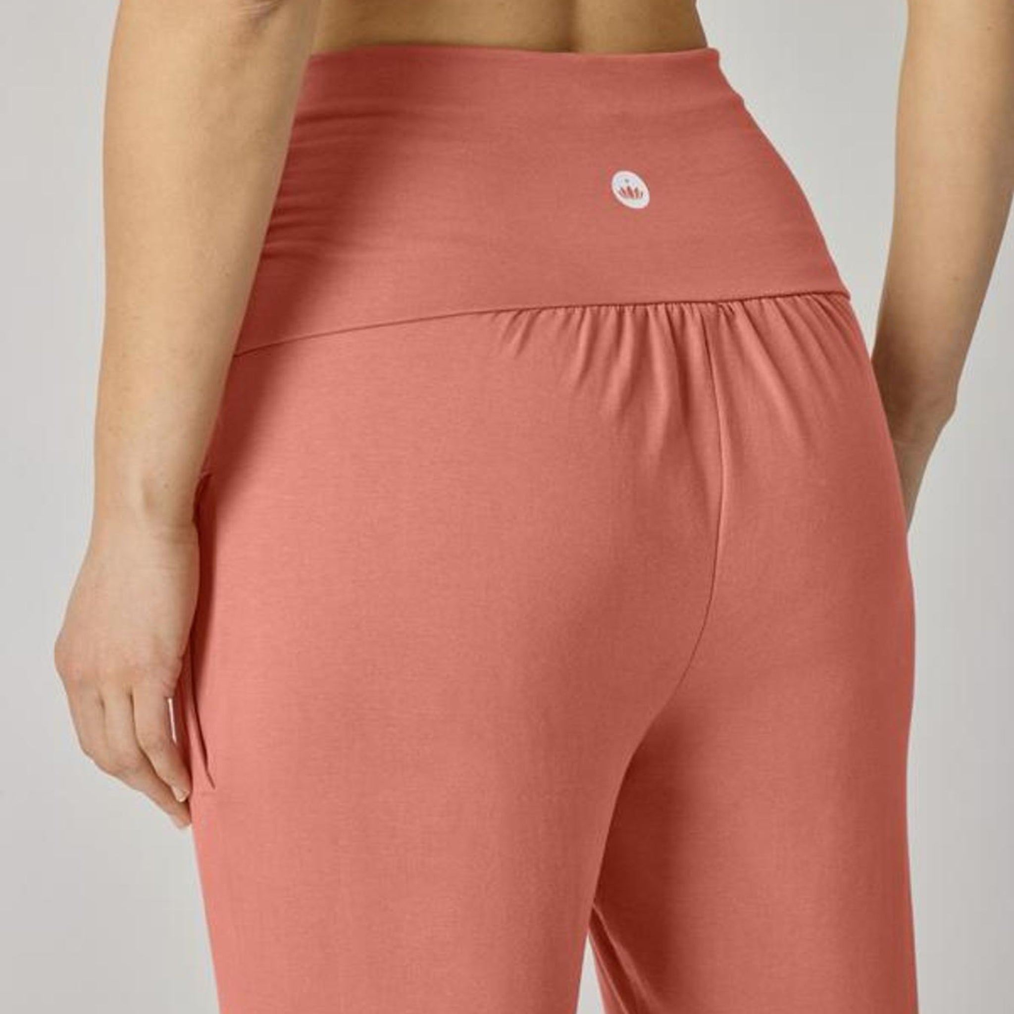 Rückansicht einer Person in einer korallenfarbenen Hose mit einem kleinen Logo auf der Rückseite.