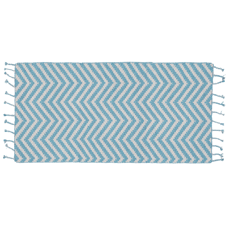 Ein rechteckiger Teppich mit blau-weißem Zickzackmuster und Quastenfransen an den beiden kürzeren Kanten auf weißem Grund.