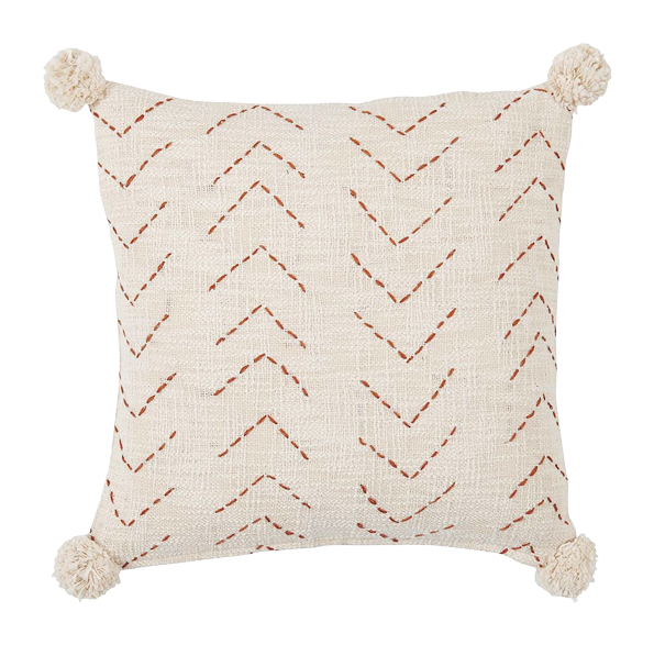 Beiges Kissen mit roten Chevron-Nähten und Bommelquasten an den Ecken.