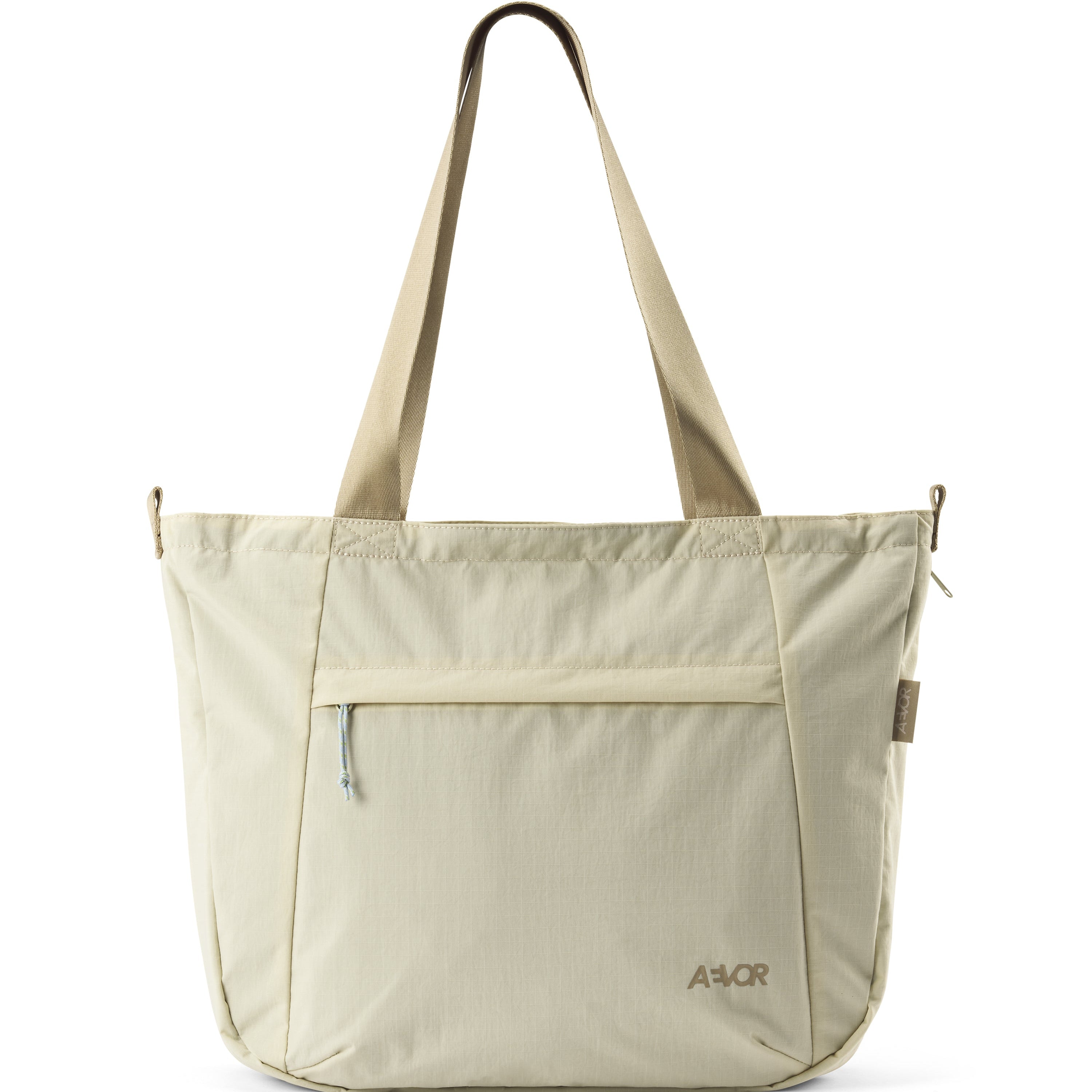 Eine beigefarbene Tragetasche mit zwei Schulterriemen, einer Vordertasche mit Reißverschluss und dem aufgedruckten Markennamen AEVOR in der unteren rechten Ecke. Die Tasche hat ein minimalistisches, lässiges Design.