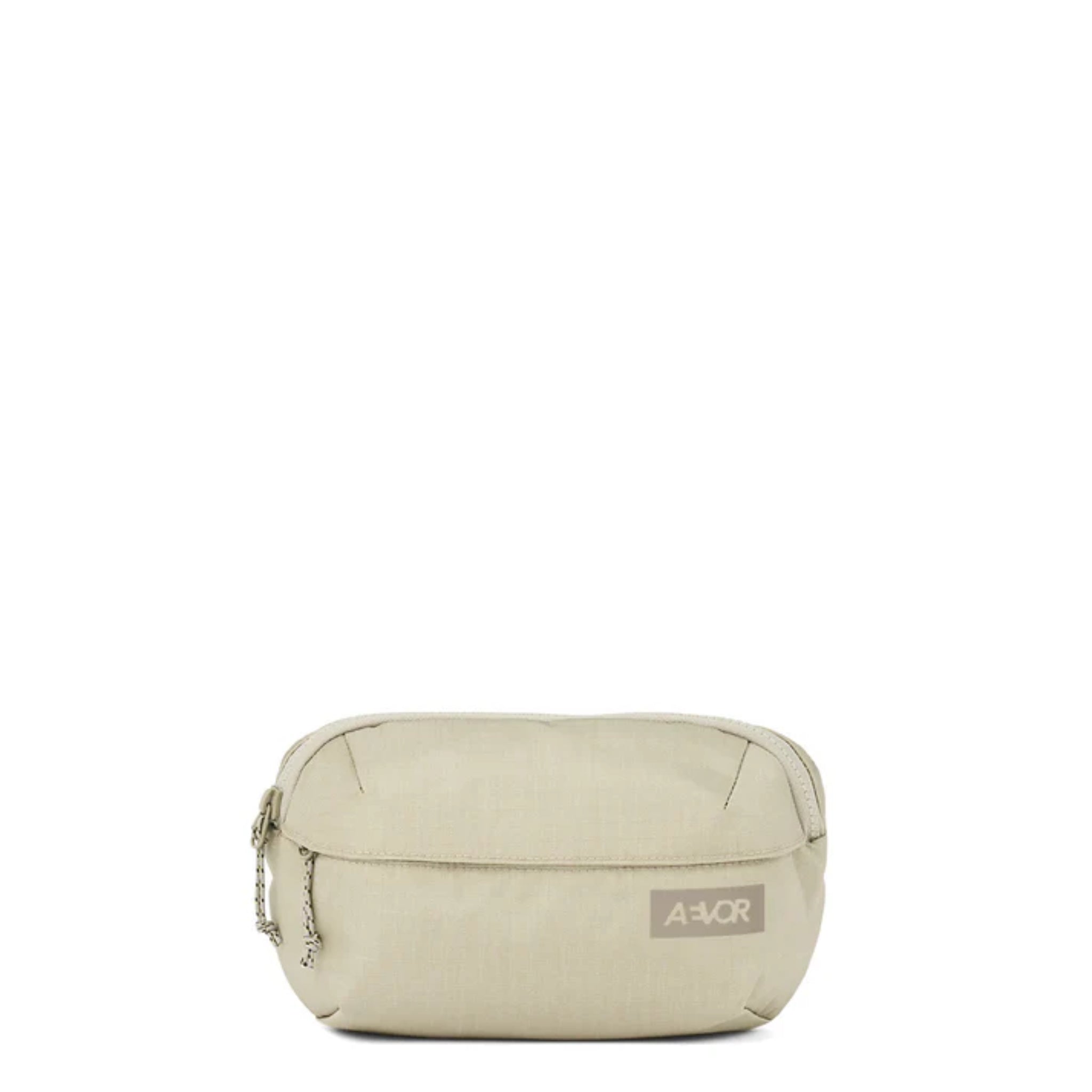 Eine kleine, beigefarbene Stofftasche mit einem Reißverschluss und einem kurzen geflochtenen Band an der Seite. Auf der Vorderseite befindet sich ein rechteckiger Aufnäher mit dem Markennamen Aevor in weißen Buchstaben.