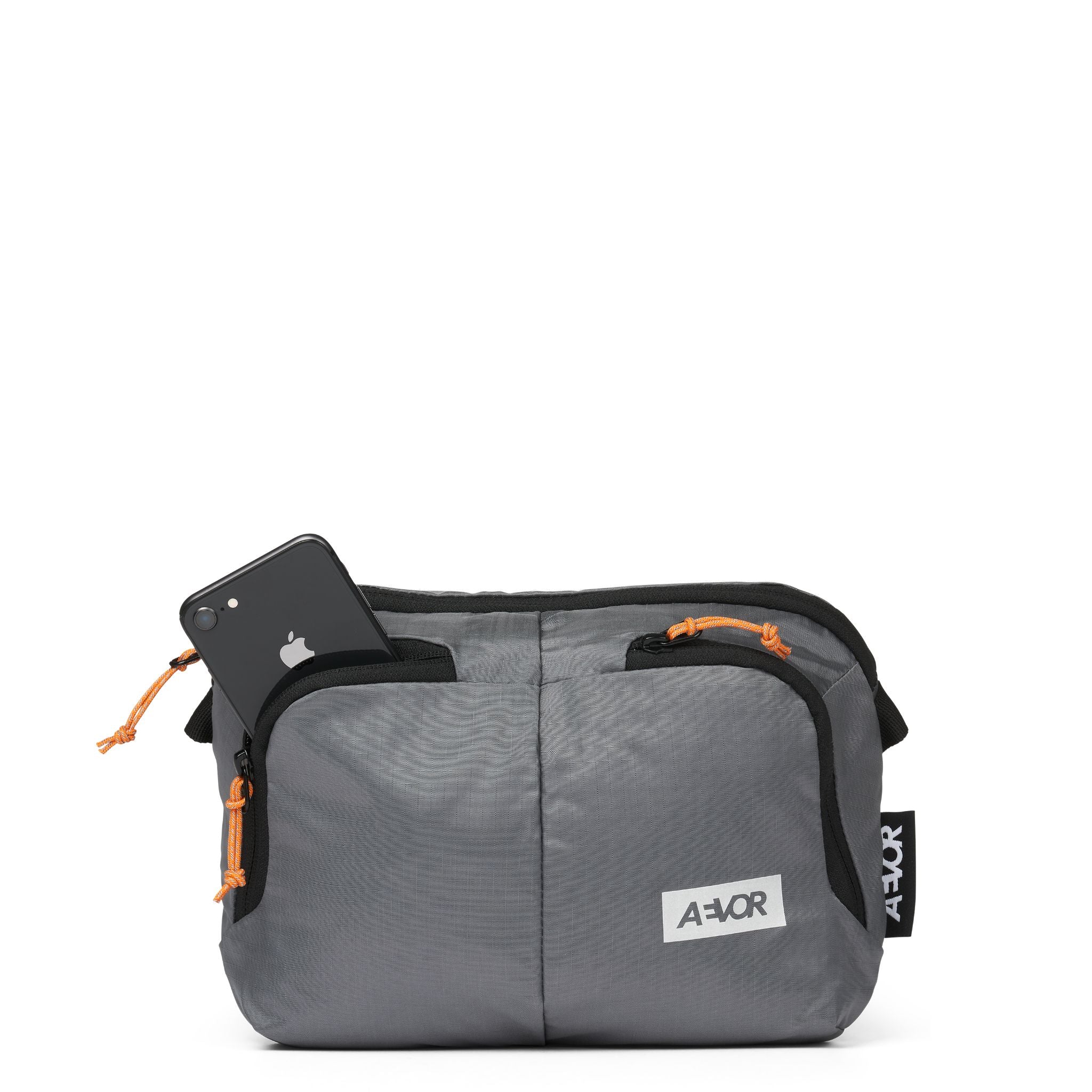 Graue Bauchtasche mit schwarz-orangen Reißverschlüssen, darin ein schwarzes Smartphone sichtbar, mit AEVOR-Logo.