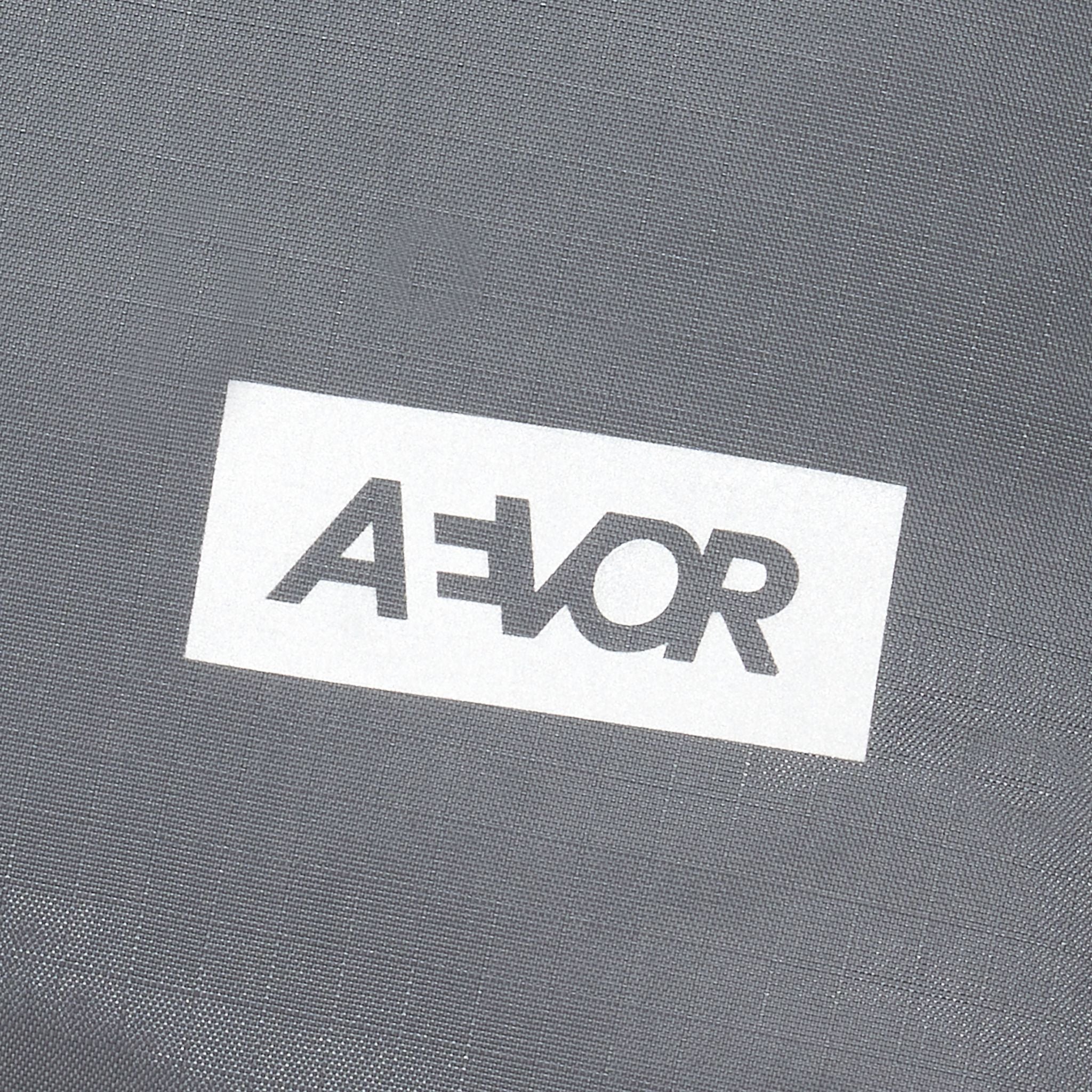 Graues Textil mit einem weißen Etikett, auf dem in schwarzer Schrift "AEVOR" steht.