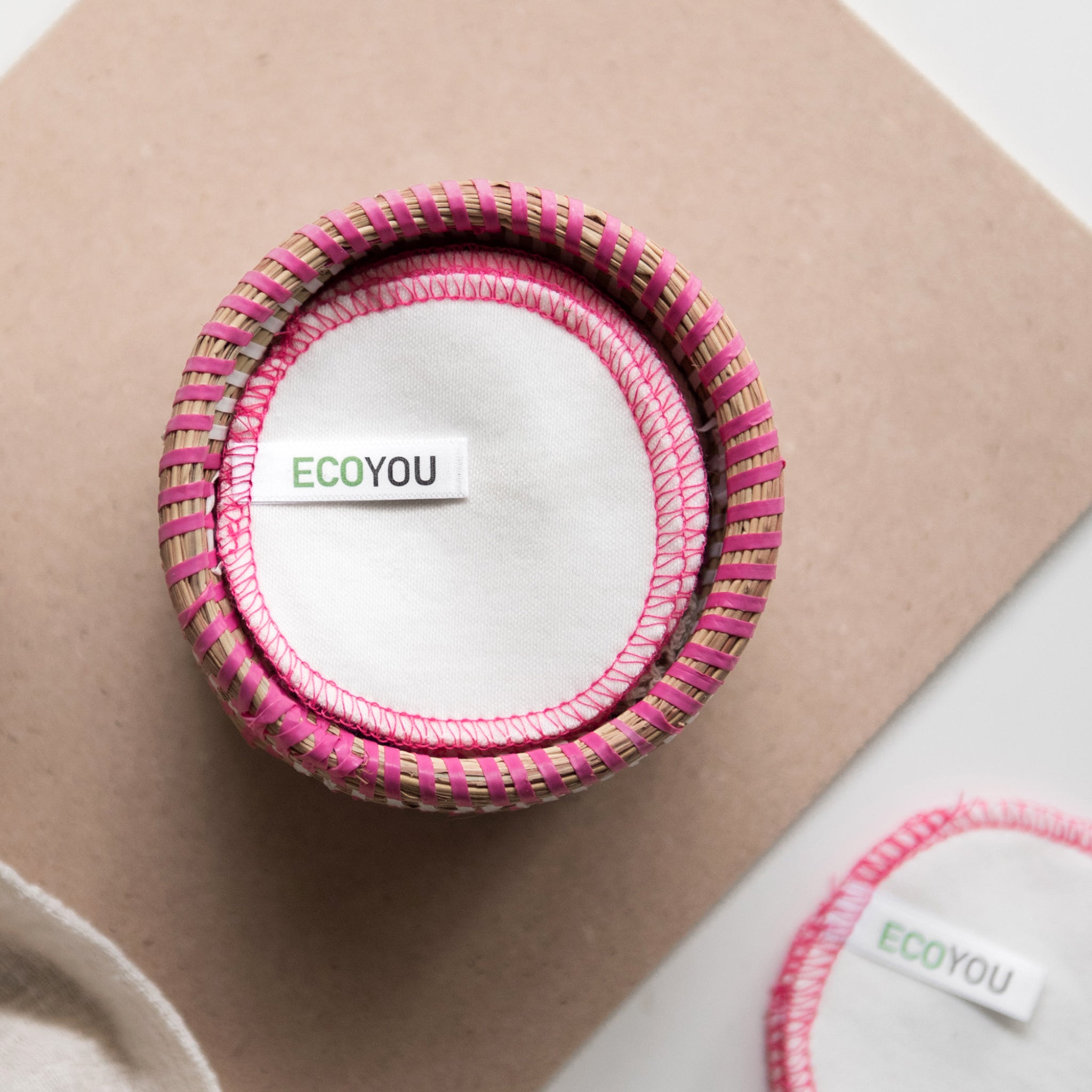 Runde Abschminkpads in einem rosa Korb mit Label "ECOYOU" auf einem beigen Untergrund.