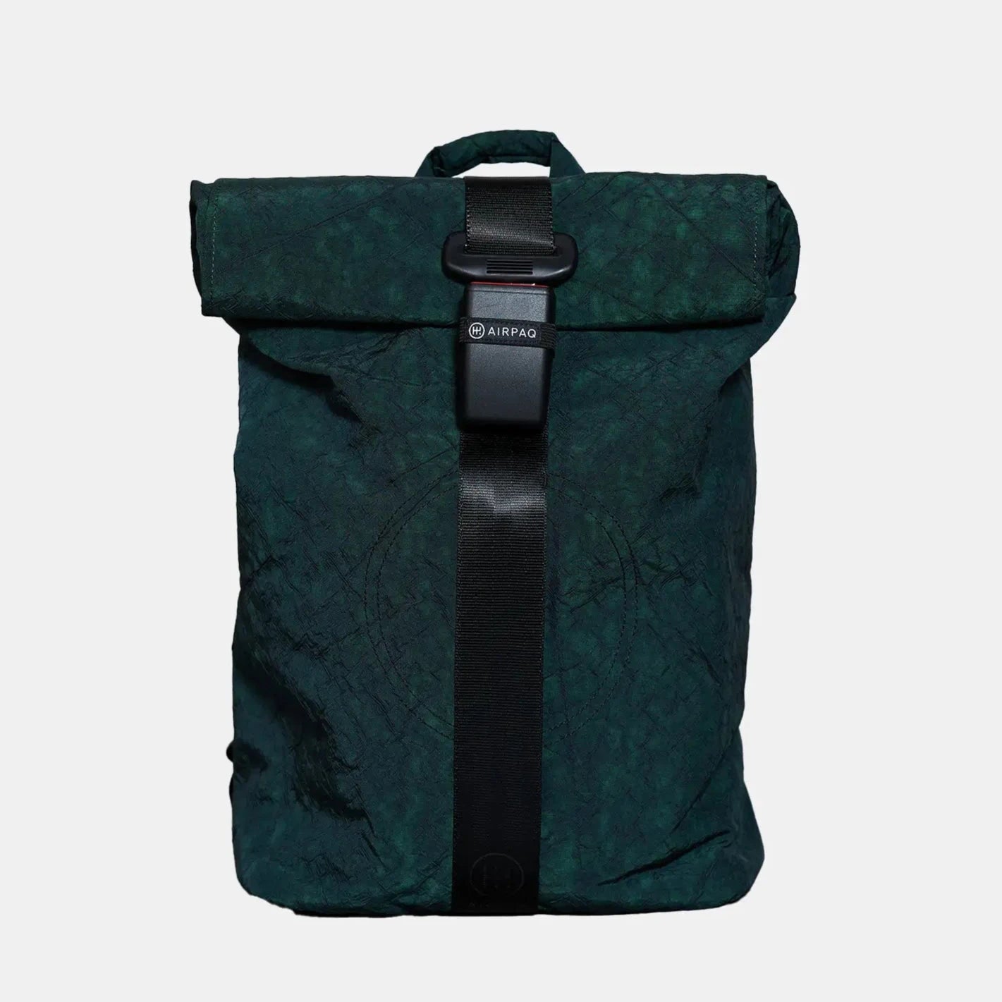 Dunkelgrüner Rolltop-Rucksack mit schwarzem Riemen und Kunststoffschnallenverschluss, mit einem Henkel an der Oberseite vor einem schlichten hellen Hintergrund.