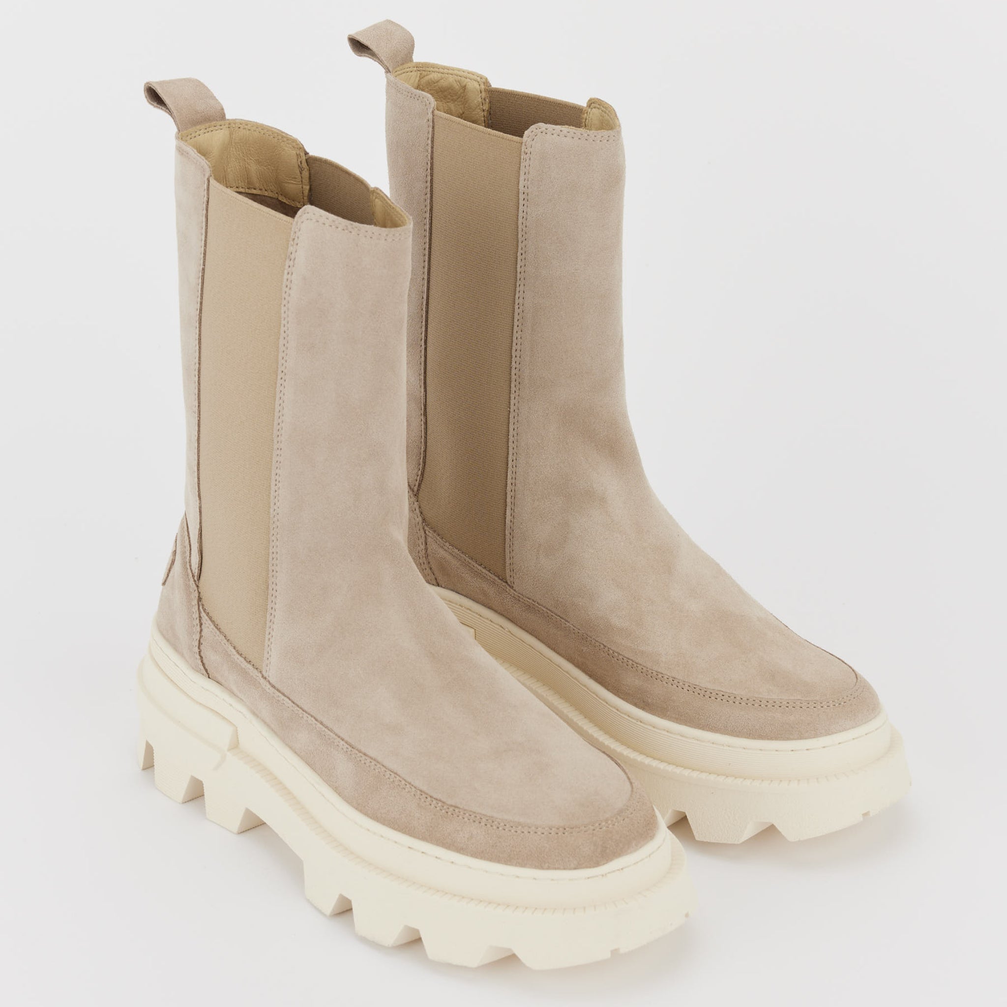 Beige Wildleder-Boots mit dicker, cremefarbener Sohle und elastischen Einsätzen an den Seiten.