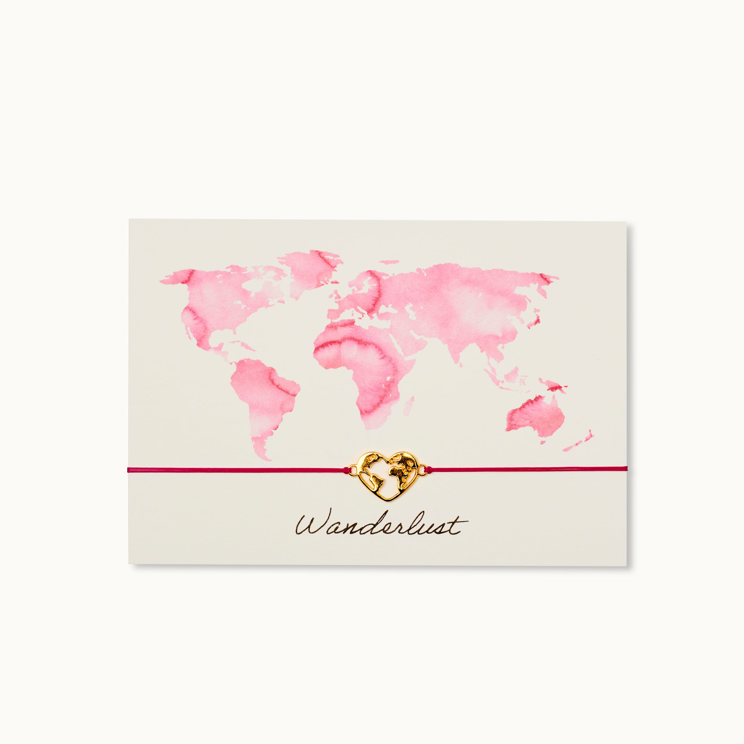 Karte mit rosa Weltkarte, einem goldenen Herzanhänger auf rotem Band und der Aufschrift "Wanderlust".