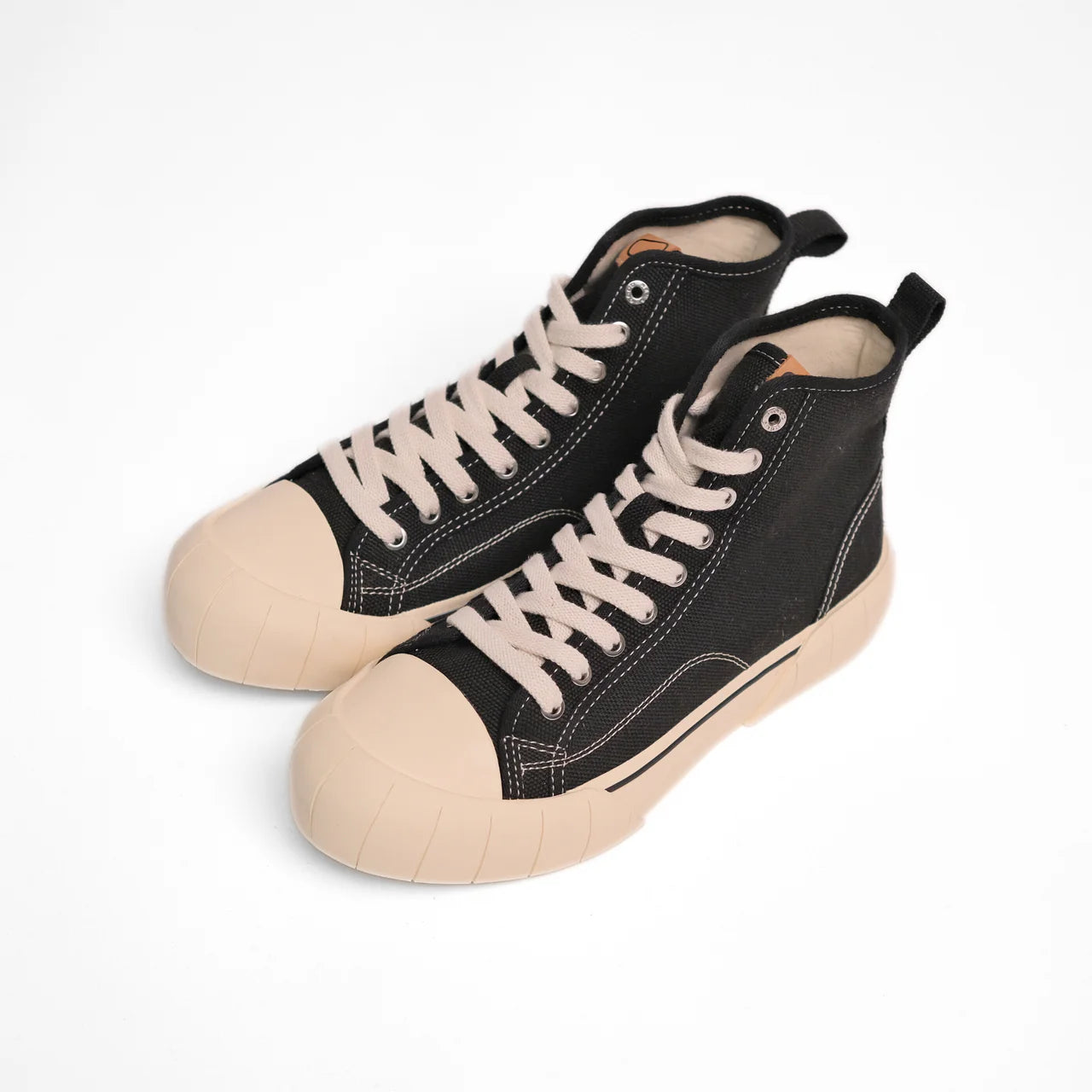 Schwarze High-Top-Sneaker mit cremefarbenen Sohlen und Schnürsenkeln, seitlich fotografiert auf weißem Hintergrund.