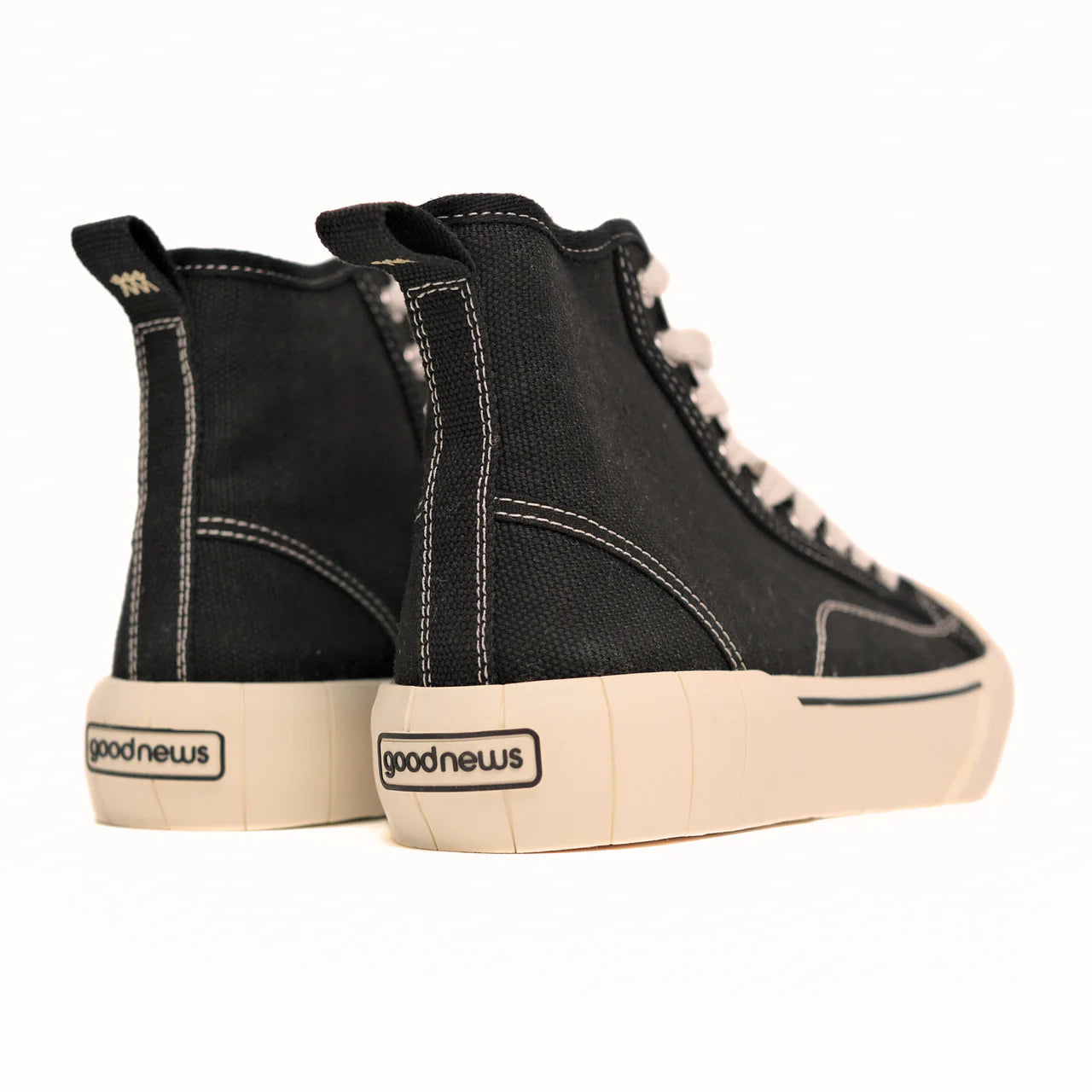 Schwarze High-Top-Sneaker mit weißen Nähten und cremefarbenen Sohlen, Marke "goodnews" sichtbar auf der Ferse.