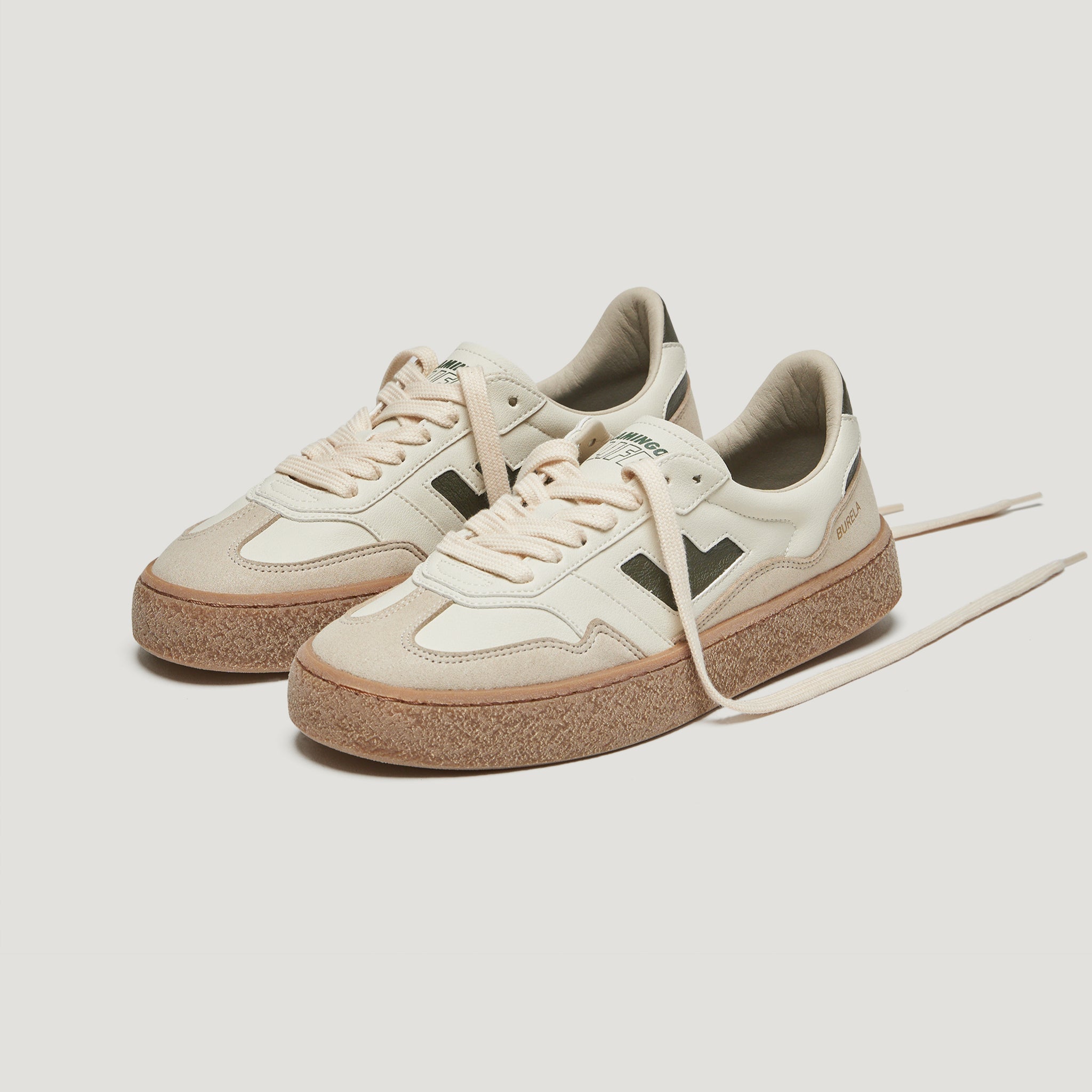 Zwei cremefarbene Sneakers mit brauner Sohle und schwarzen Details auf weißem Hintergrund.