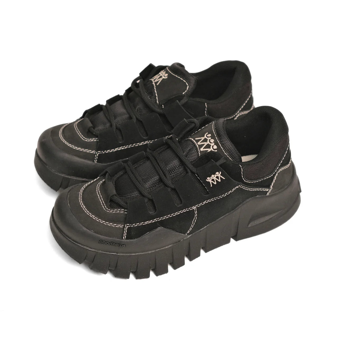 Schwarze Sneaker mit dicker Sohle und weißen Nähten auf weißem Hintergrund.