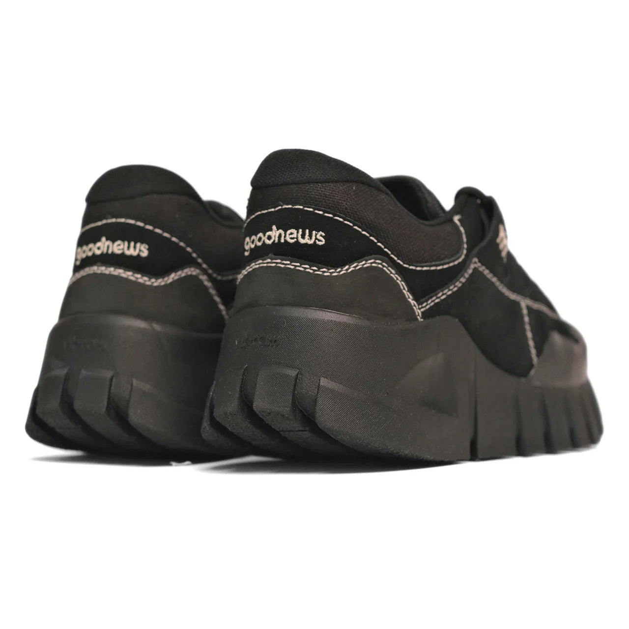 Schwarze Sneaker mit dicker Sohle und "goodnews"-Logo auf der Ferse, von hinten fotografiert.