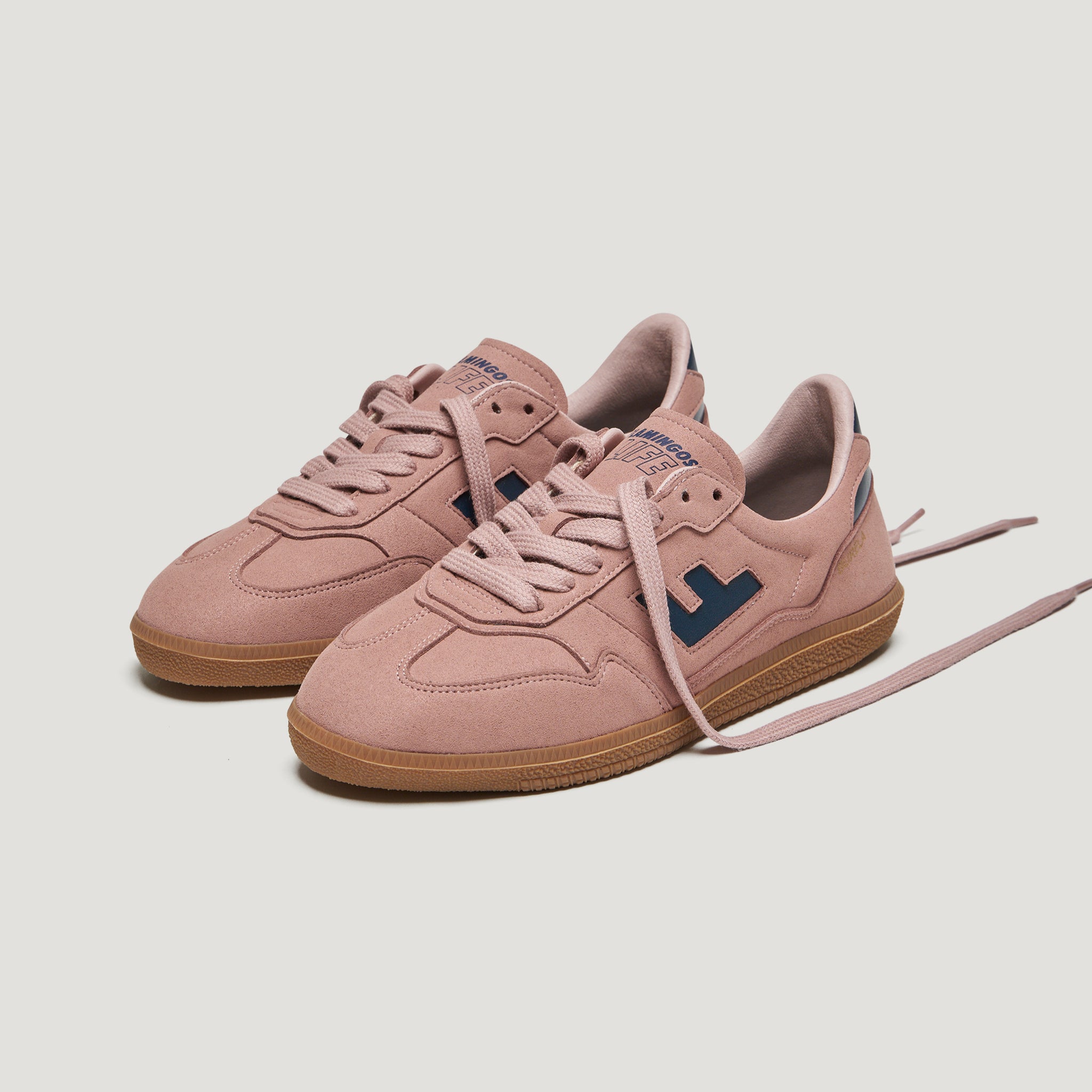 Rosa Sneaker mit blauen Details und brauner Sohle auf weißem Hintergrund.