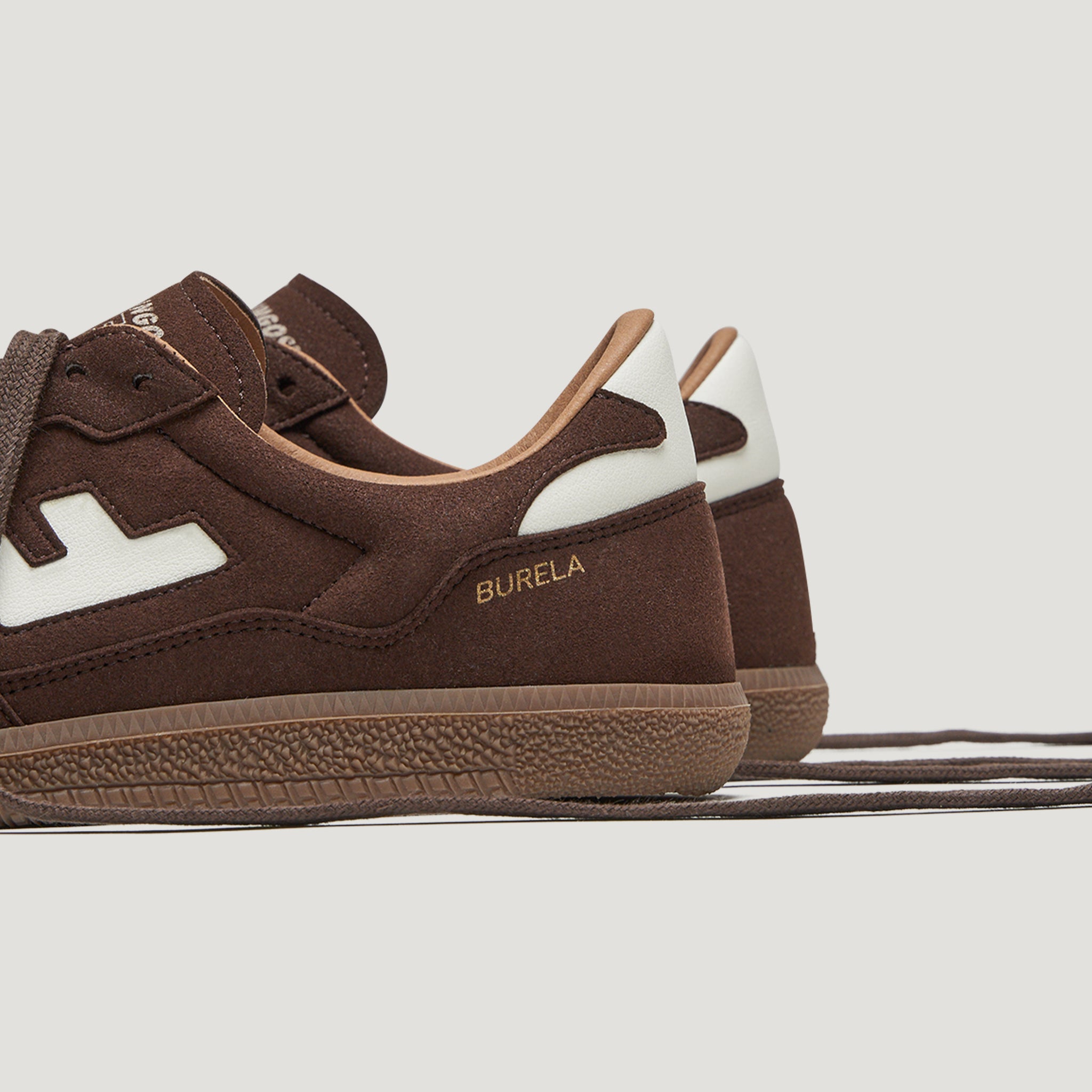 Braune Sneaker aus Wildleder mit weißem Akzent und der Aufschrift "BURELA" an der Seite.