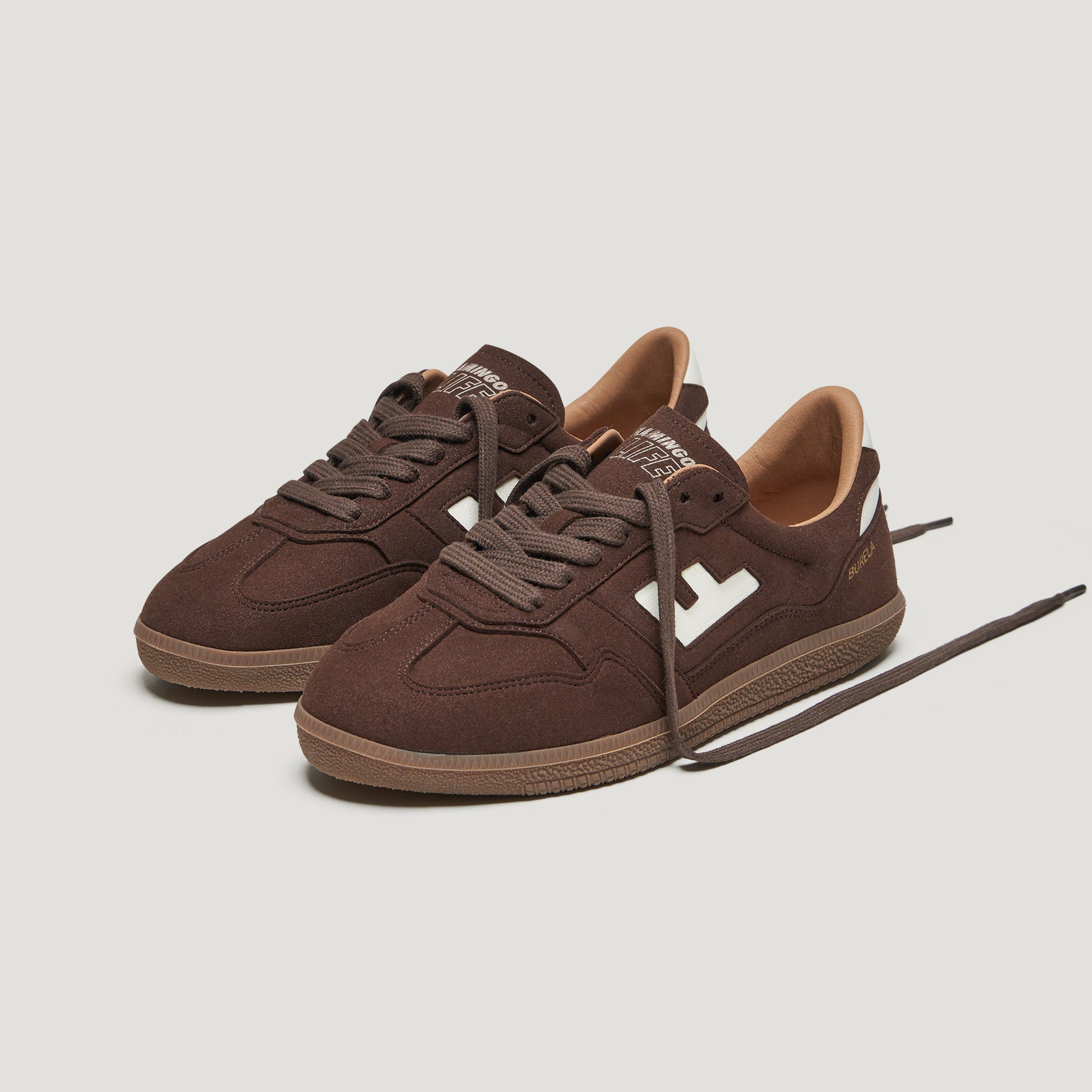 Braune Sneaker mit weißen Details und braunen Schnürsenkeln auf weißem Hintergrund.