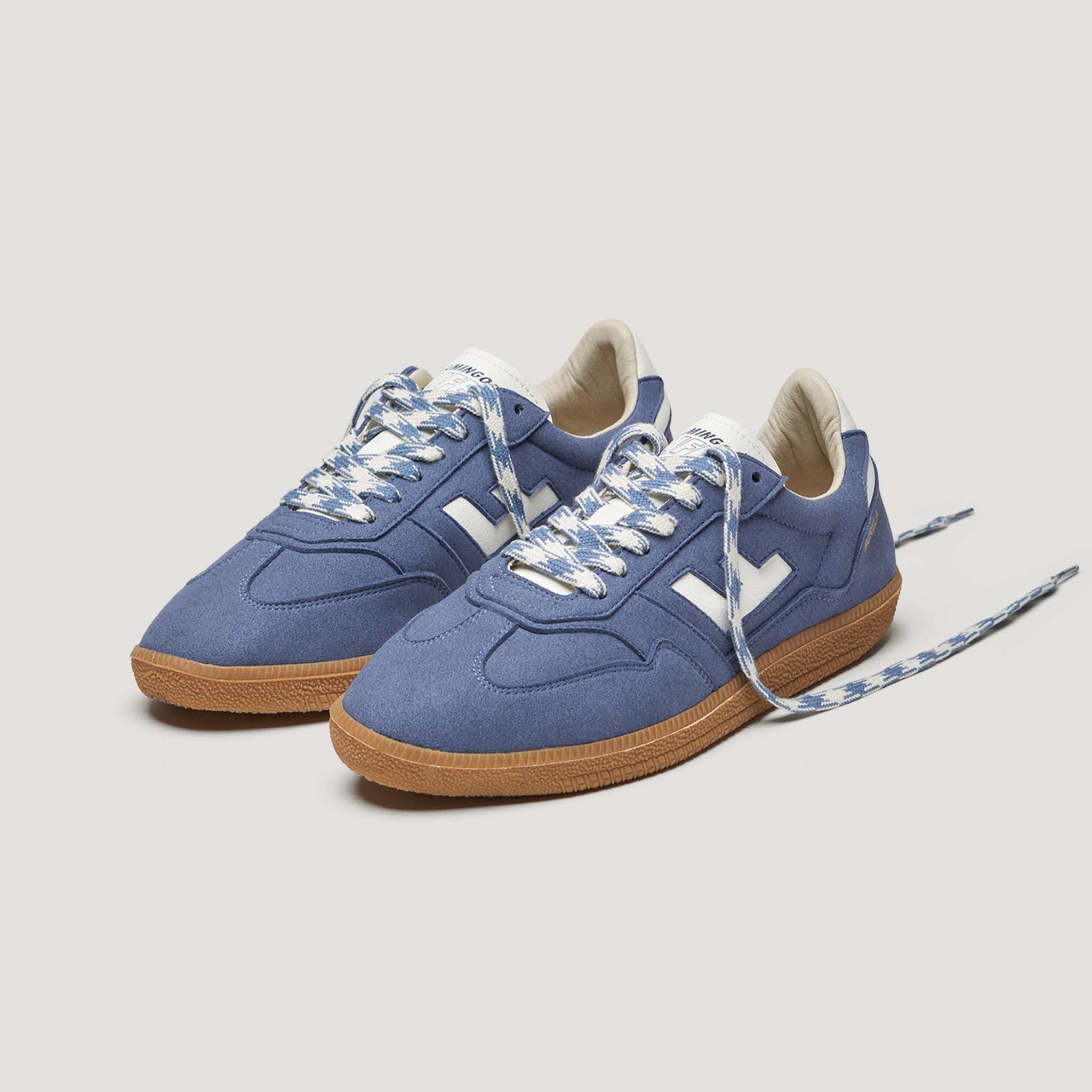 Blaue Sneaker mit weißen Schnürsenkeln und Gummisohlen, auf einem hellen Hintergrund fotografiert.