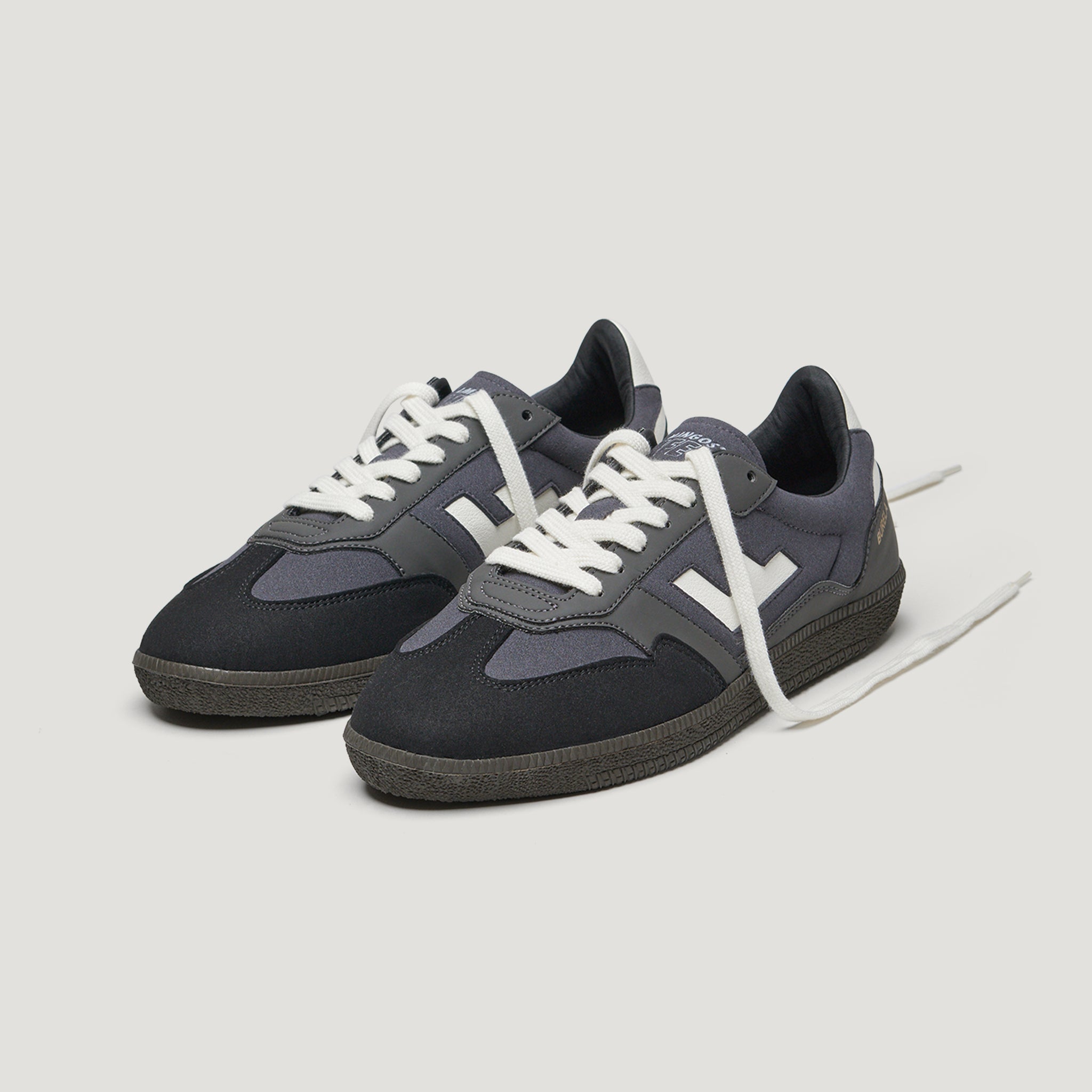 Dunkelblau-schwarze Sneaker mit weißen Schnürsenkeln und seitlichem weißem Logo auf hellem Hintergrund.