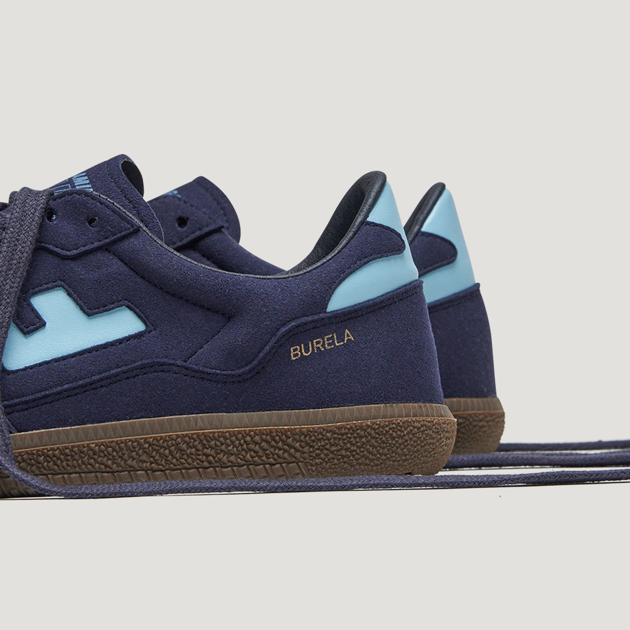 Dunkelblaue Turnschuhe mit hellblauen Akzenten und brauner Sohle, seitlich der Schriftzug "BURELA".