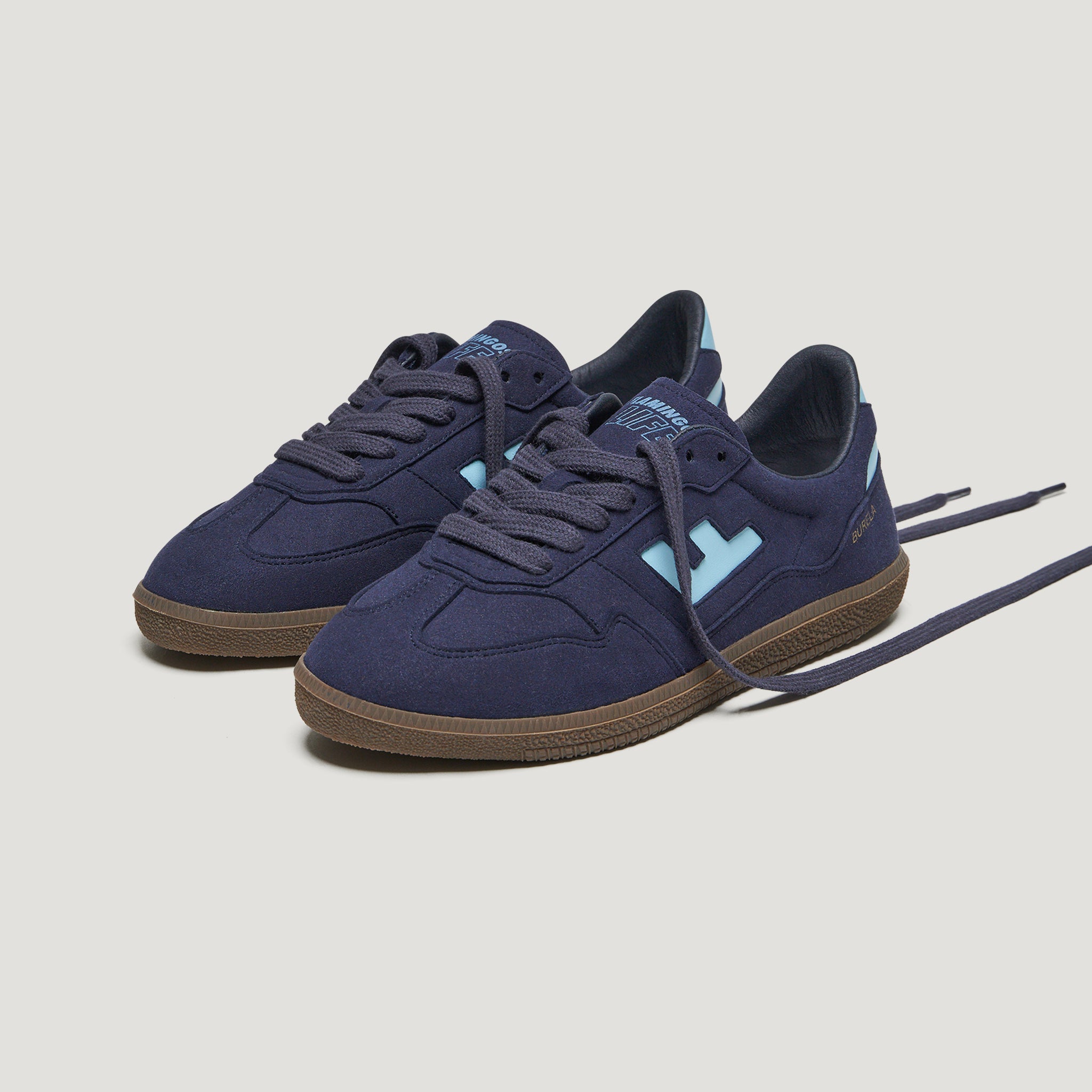 Dunkelblaue Sneakers mit hellblauen Details und brauner Sohle auf weißem Hintergrund.