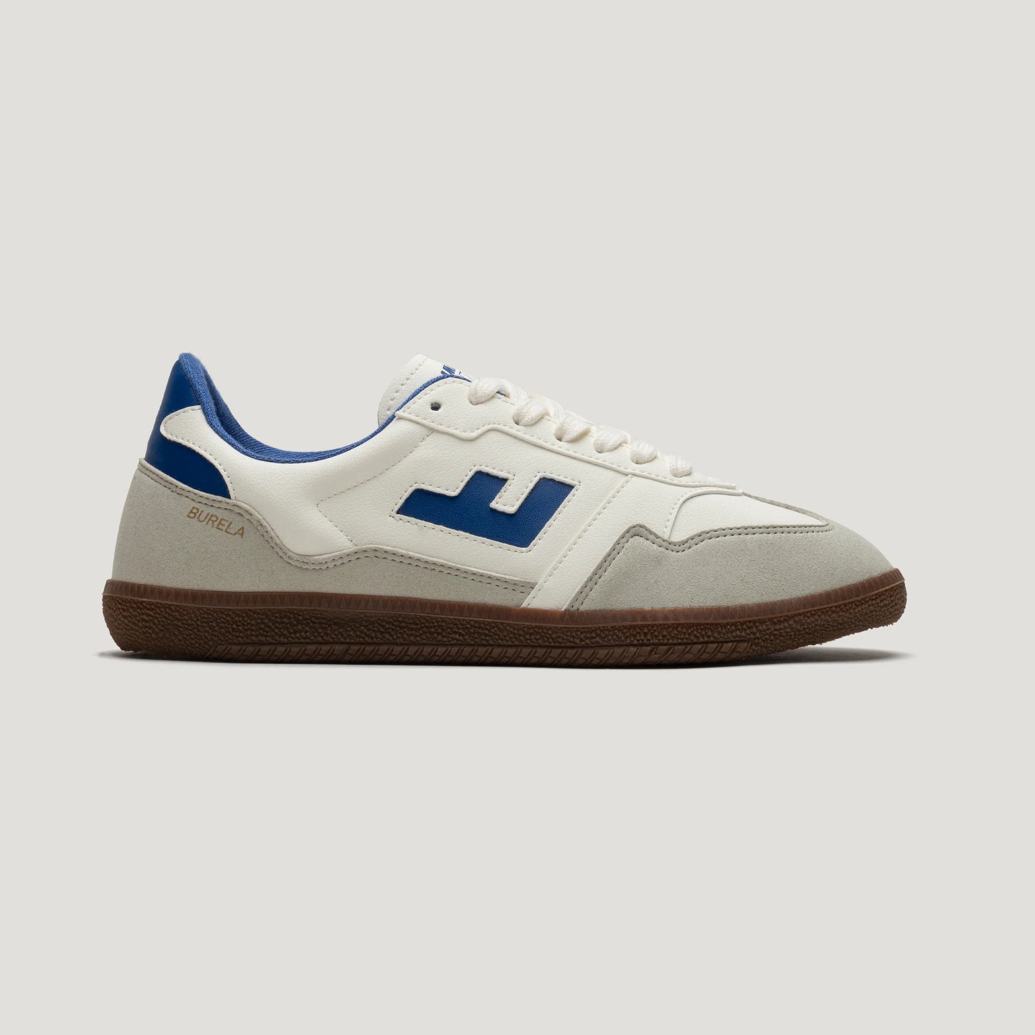Weißer Sneaker mit blauen Details und brauner Sohle, seitlich von links fotografiert.