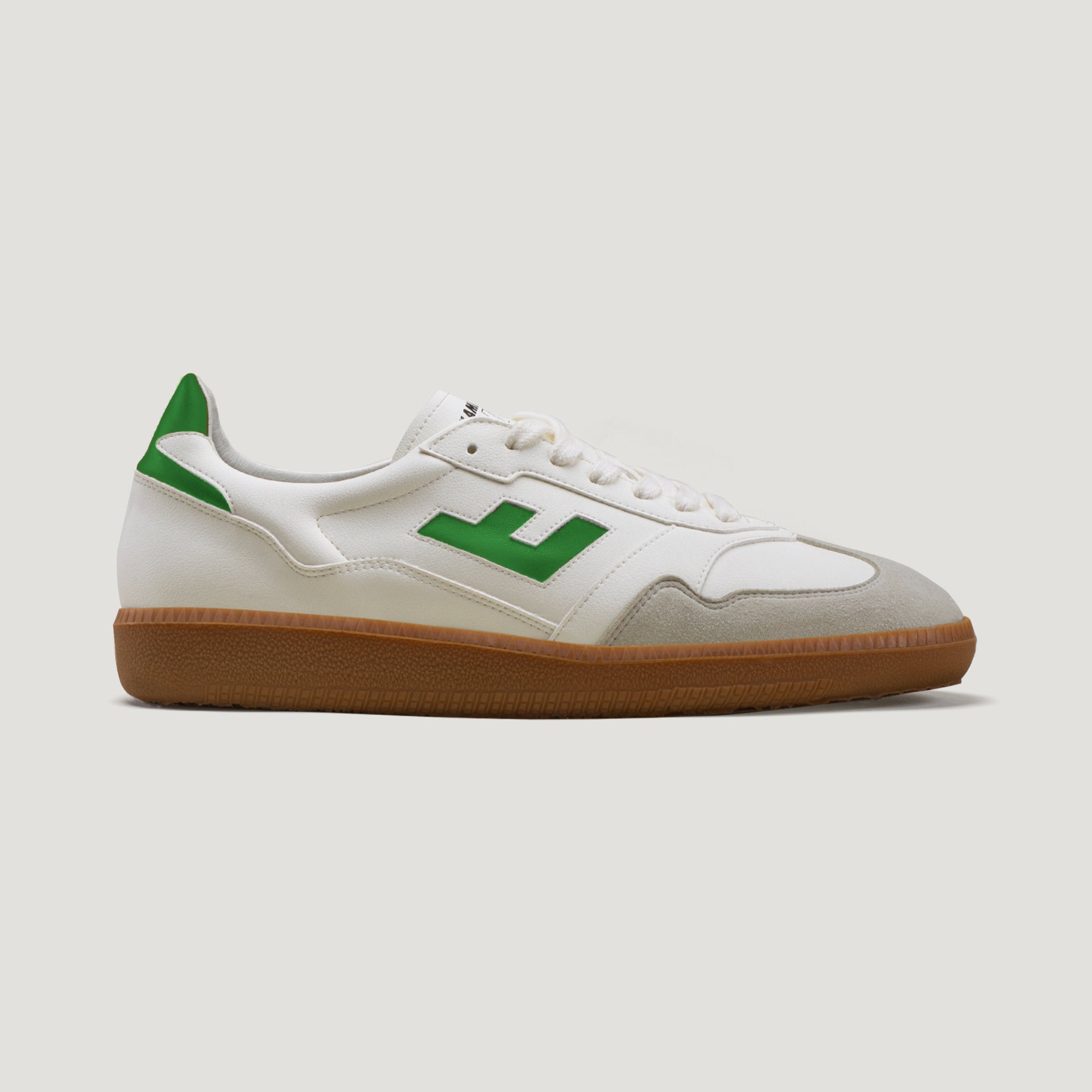 Weißer Sneaker mit grünen Akzenten und brauner Sohle, Seitenansicht auf neutralem Hintergrund.