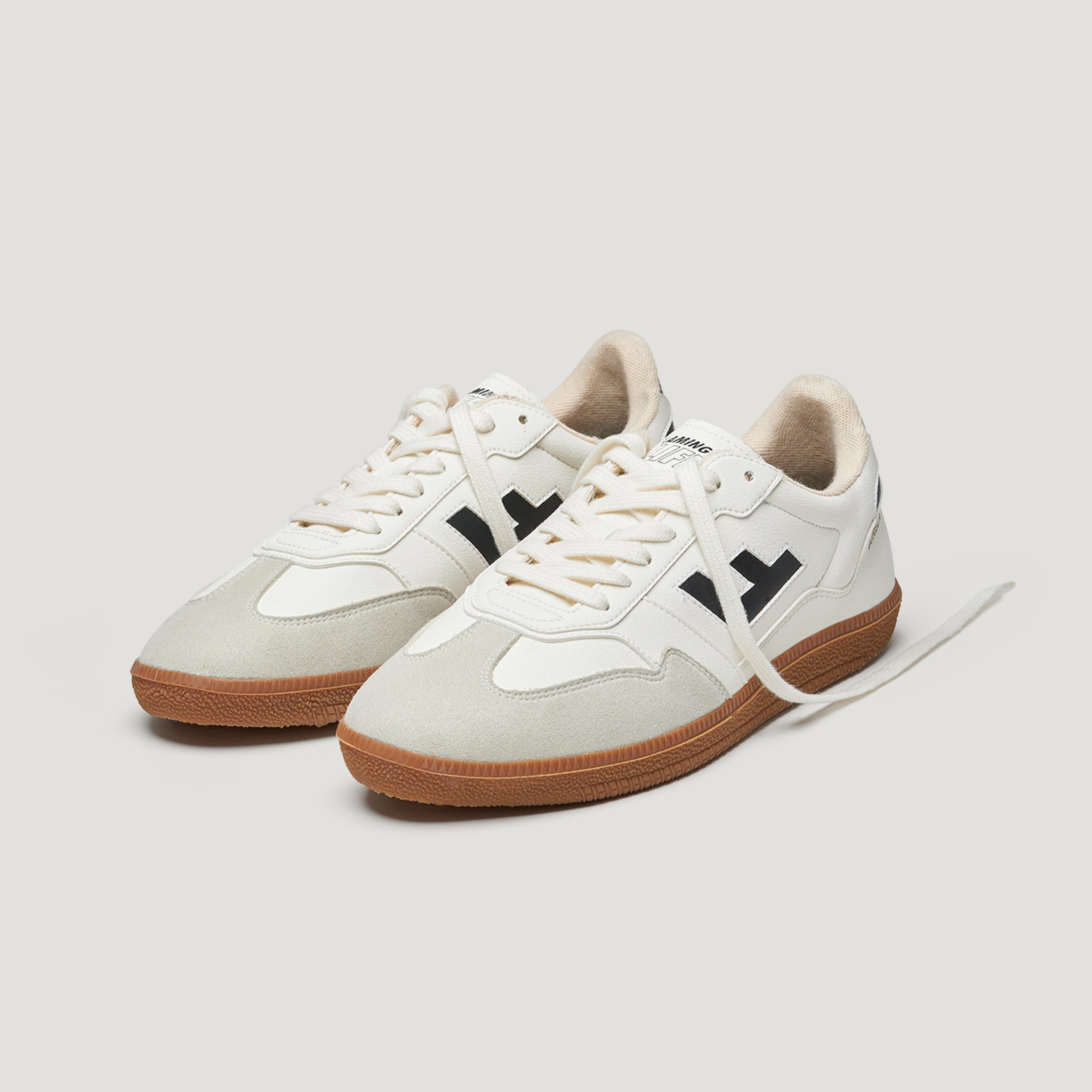 Weiße Sneaker mit brauner Sohle und schwarzen Details, stehend auf einem weißen Hintergrund.