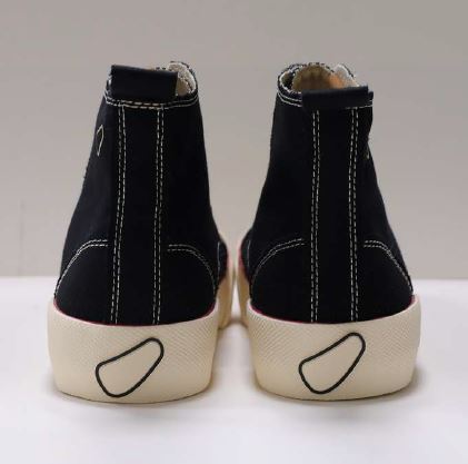 Ein Paar schwarze High-Top-Schuhe mit weißer Sohle und sichtbaren weißen Nähten von hinten.