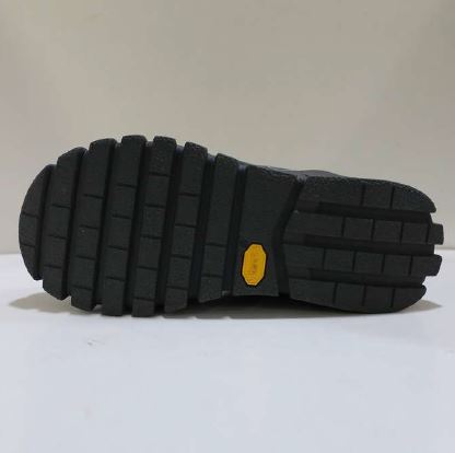Schwarze Schuhsohle mit gelbem Logo in der Mitte, auf weißem Hintergrund liegend.