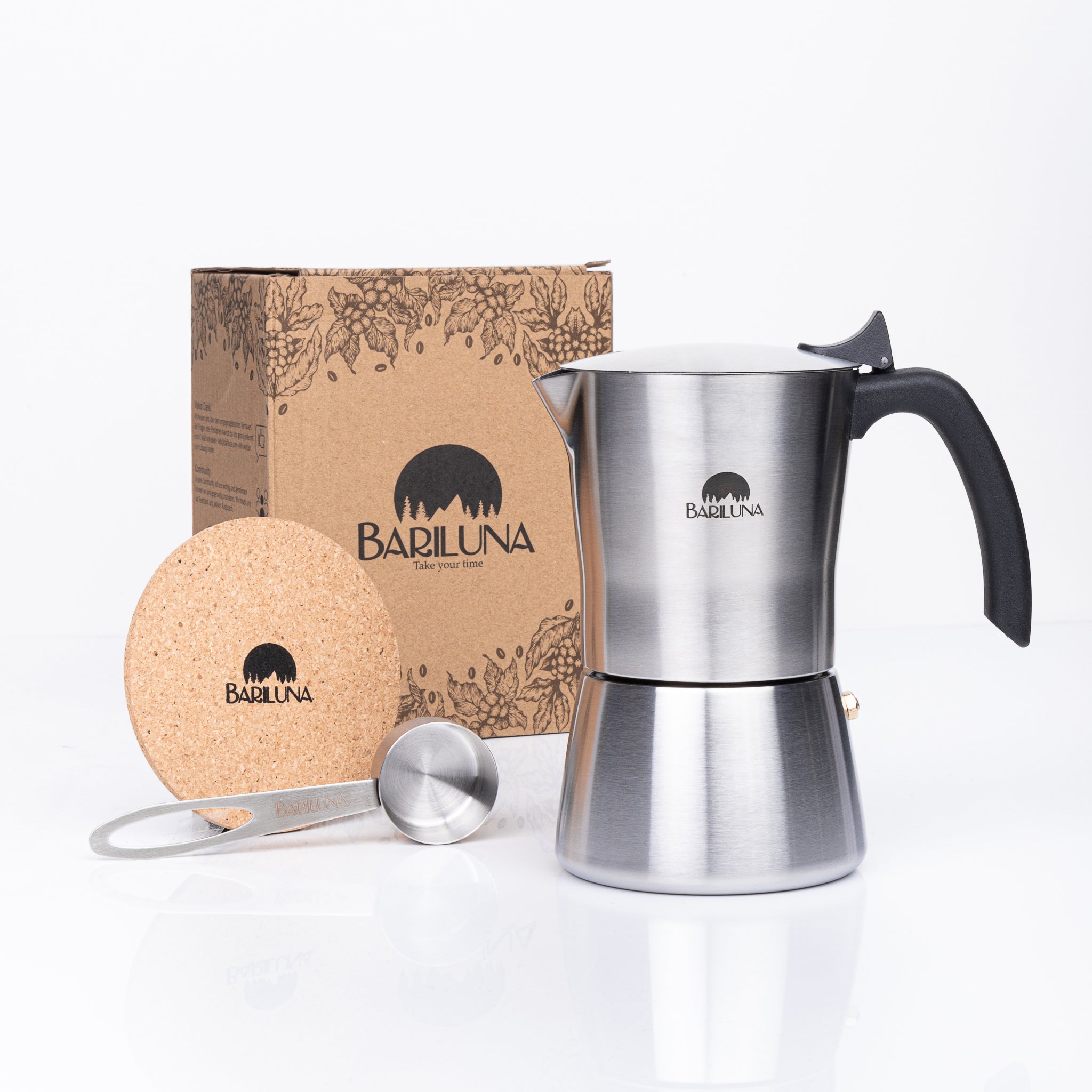 Silberne Espressokanne mit schwarzem Griff, Korkuntersetzer und Kaffeelöffel vor einem Karton mit Bariluna-Logo.
