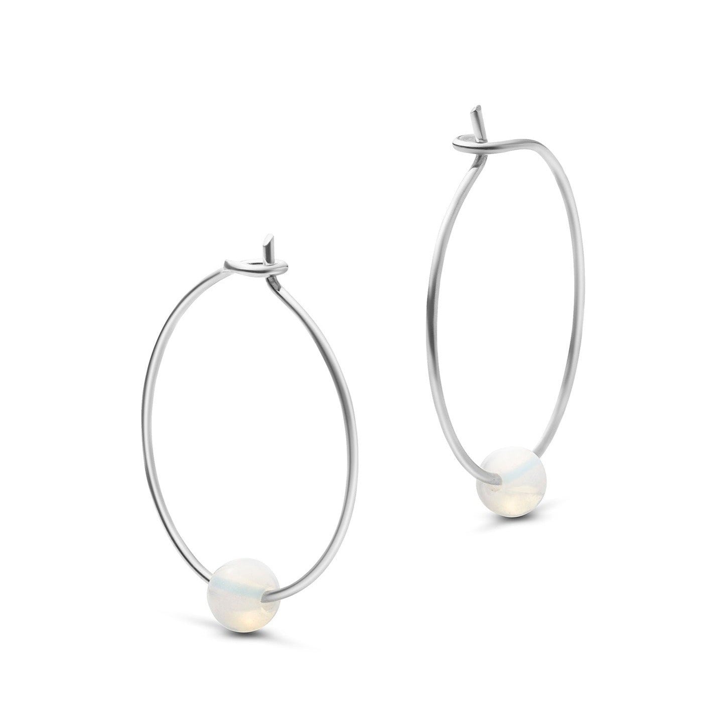 Silberne Creolen mit je einer kleinen weißen Perle am unteren Rand.