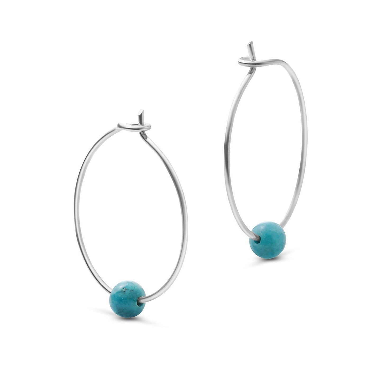 Silberne Creolen mit einer blauen Perle an jedem Ohrring vor einem weißen Hintergrund.