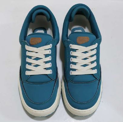 Ein Paar blaue Sneaker mit weißen Schnürsenkeln und weißen Sohlen auf weißem Hintergrund, von oben betrachtet.